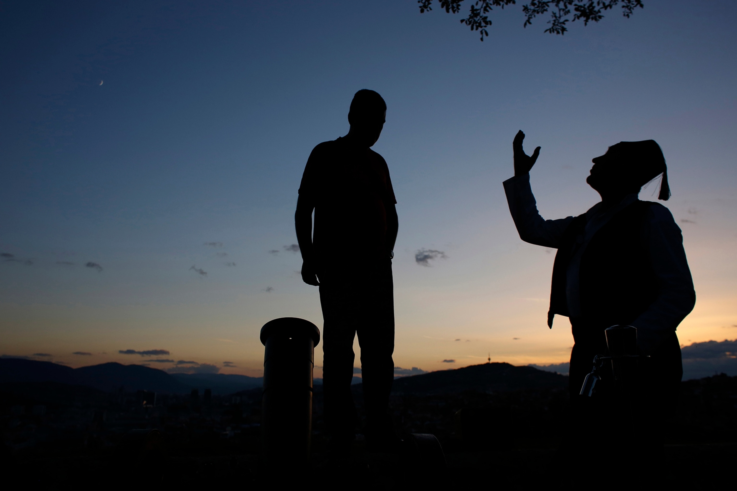 Bosnian Ramadan gunner Smail Krivic talks to a visitor as he loads his firework cannon before firing it to signal the end of dawn-to-dusk fast in Sarajevo on Wednesday evening, July 2, 2014.
