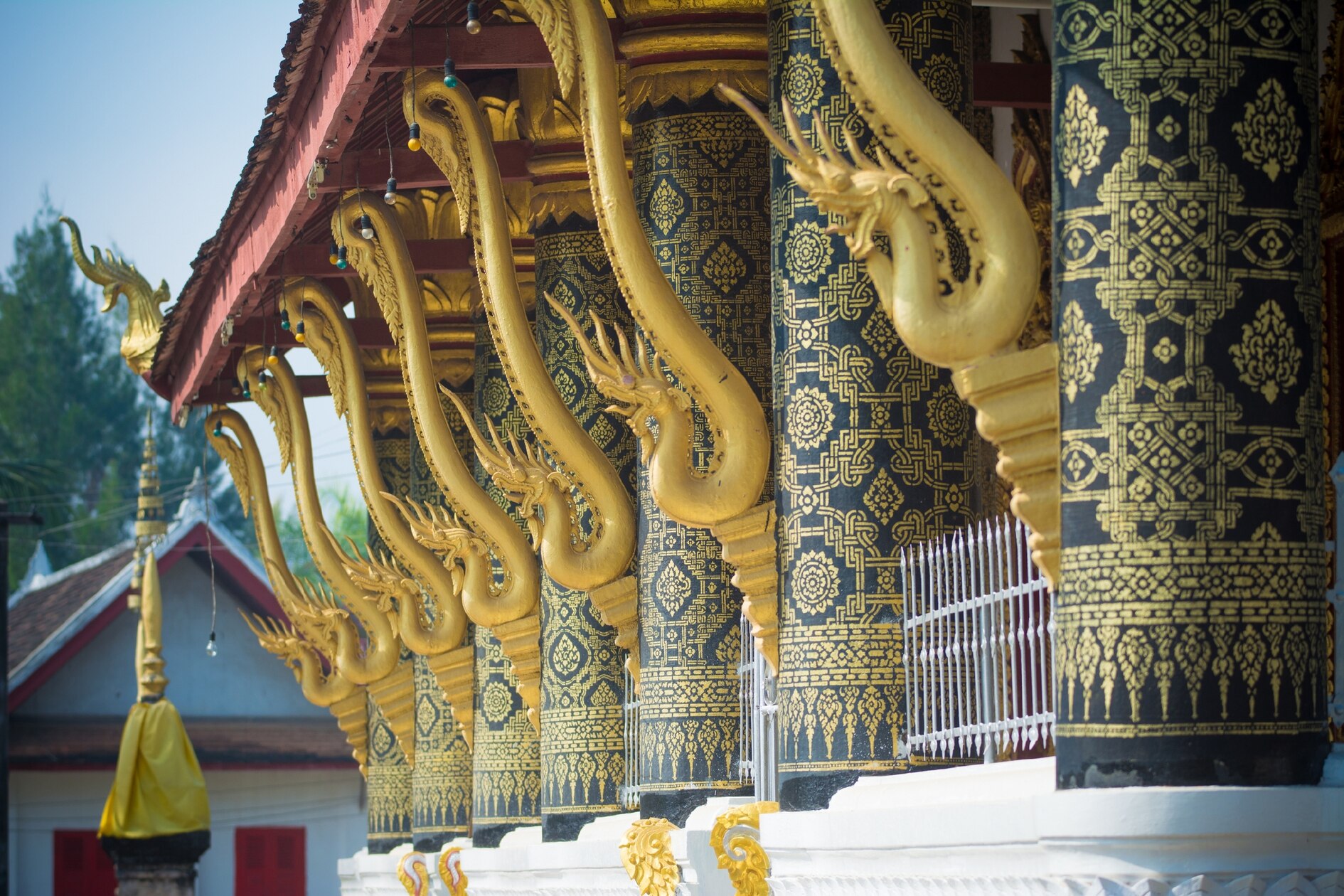 Several pillars of a temple each with their own golden naga figure