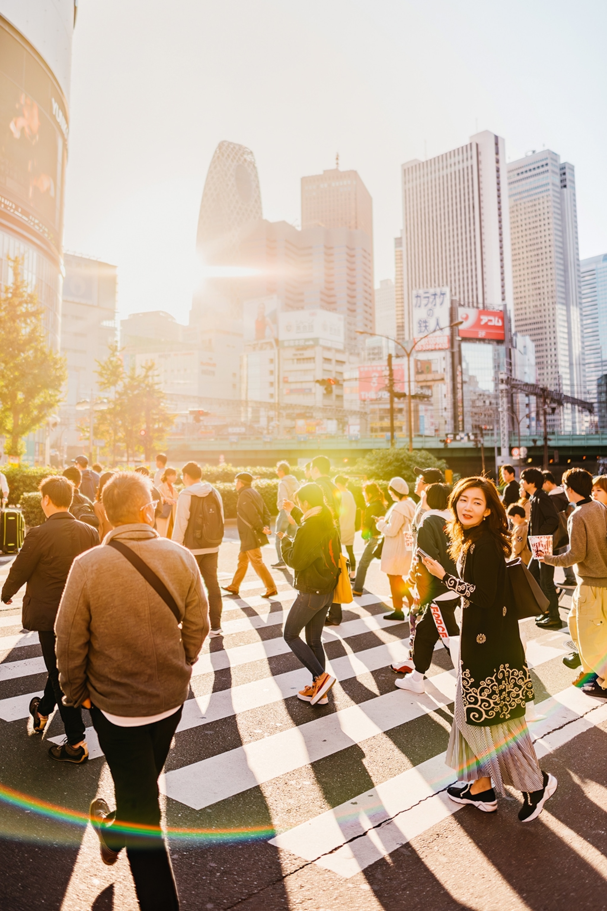 A dynamic shot of Japanese people crossing the famed Shibuya crossing in Tokyo as a sun glare hits the camera lens.