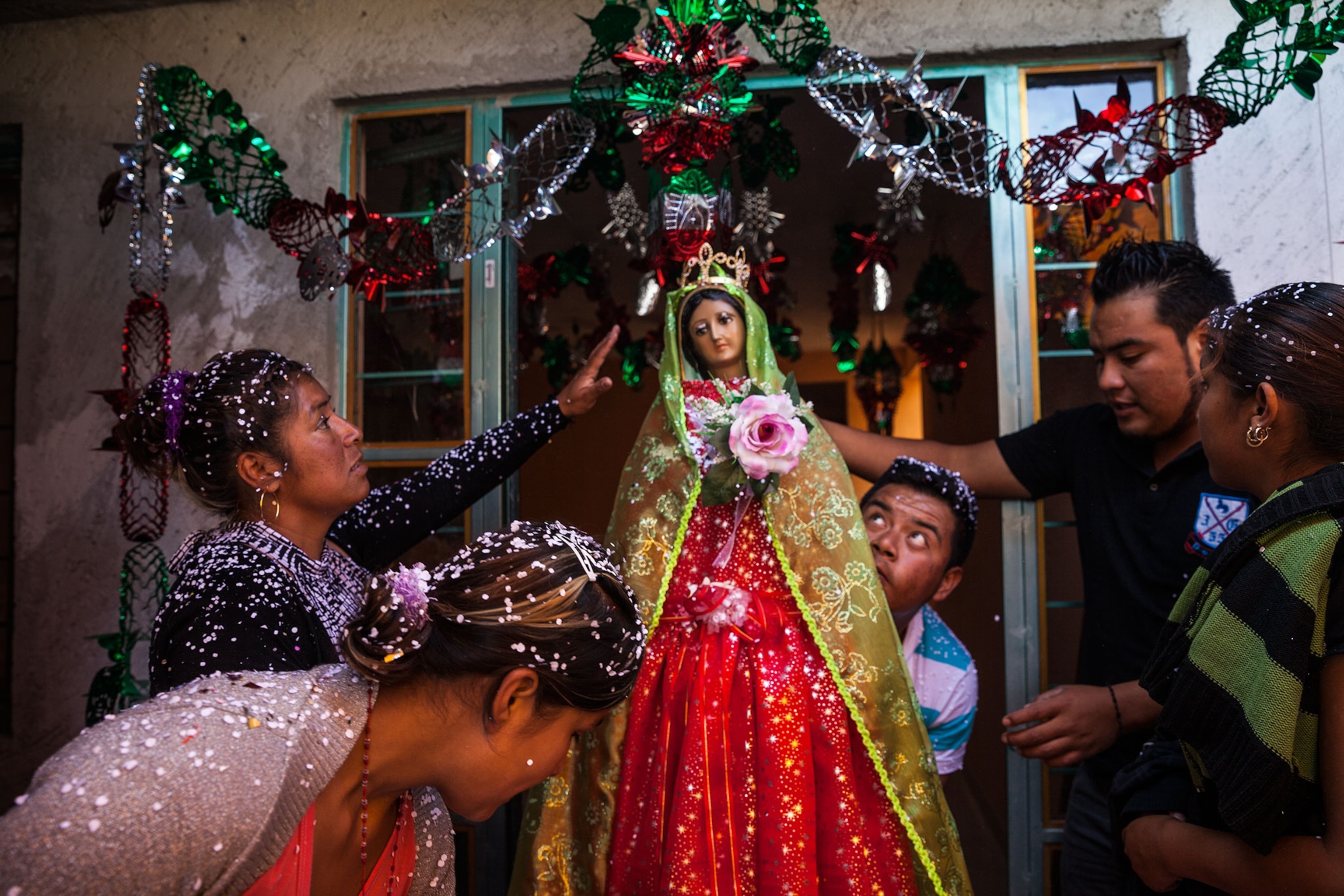 a family decorating a statue of the Virgin Mary.