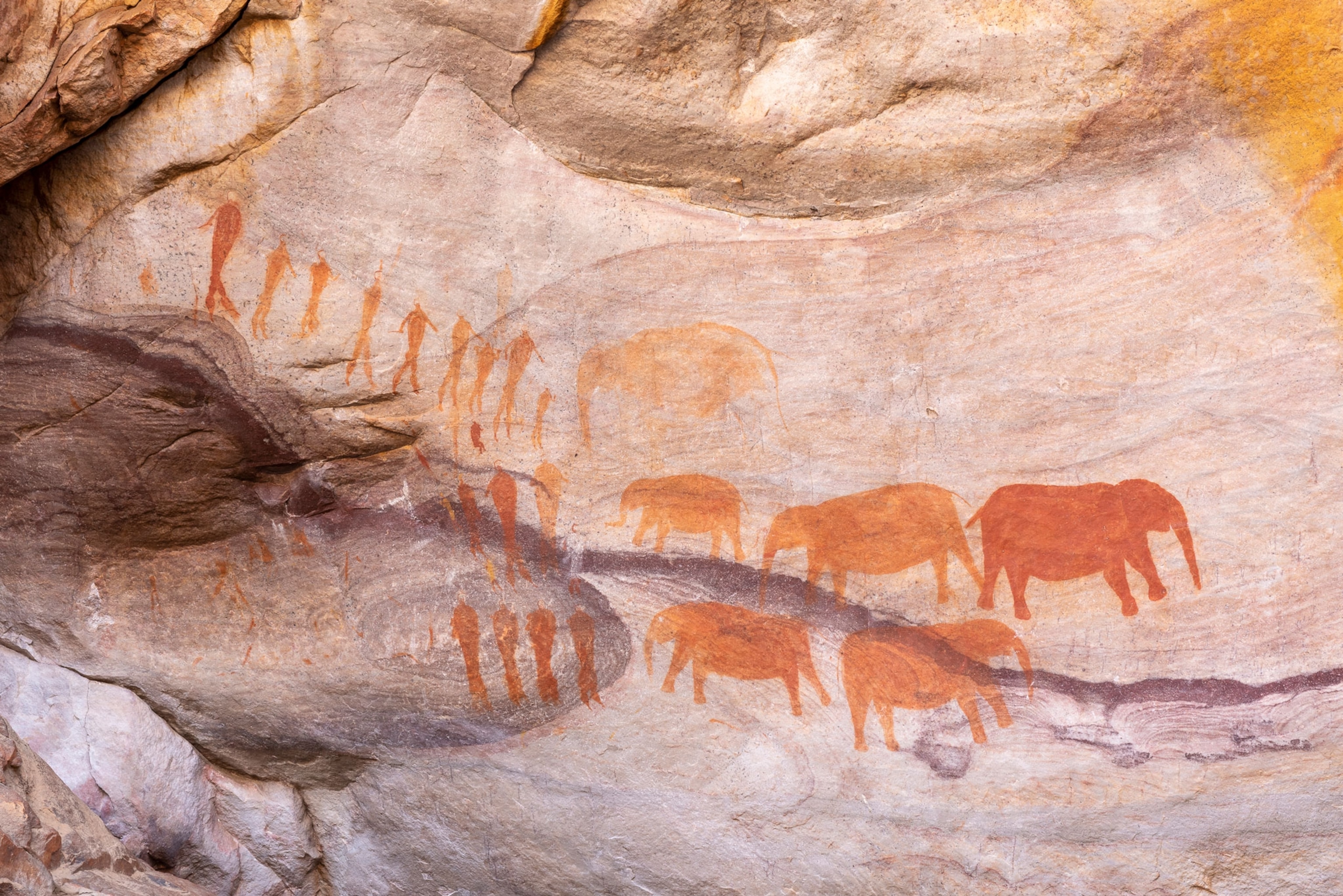 Sandstone rock formations with cave paintings of people and elephants