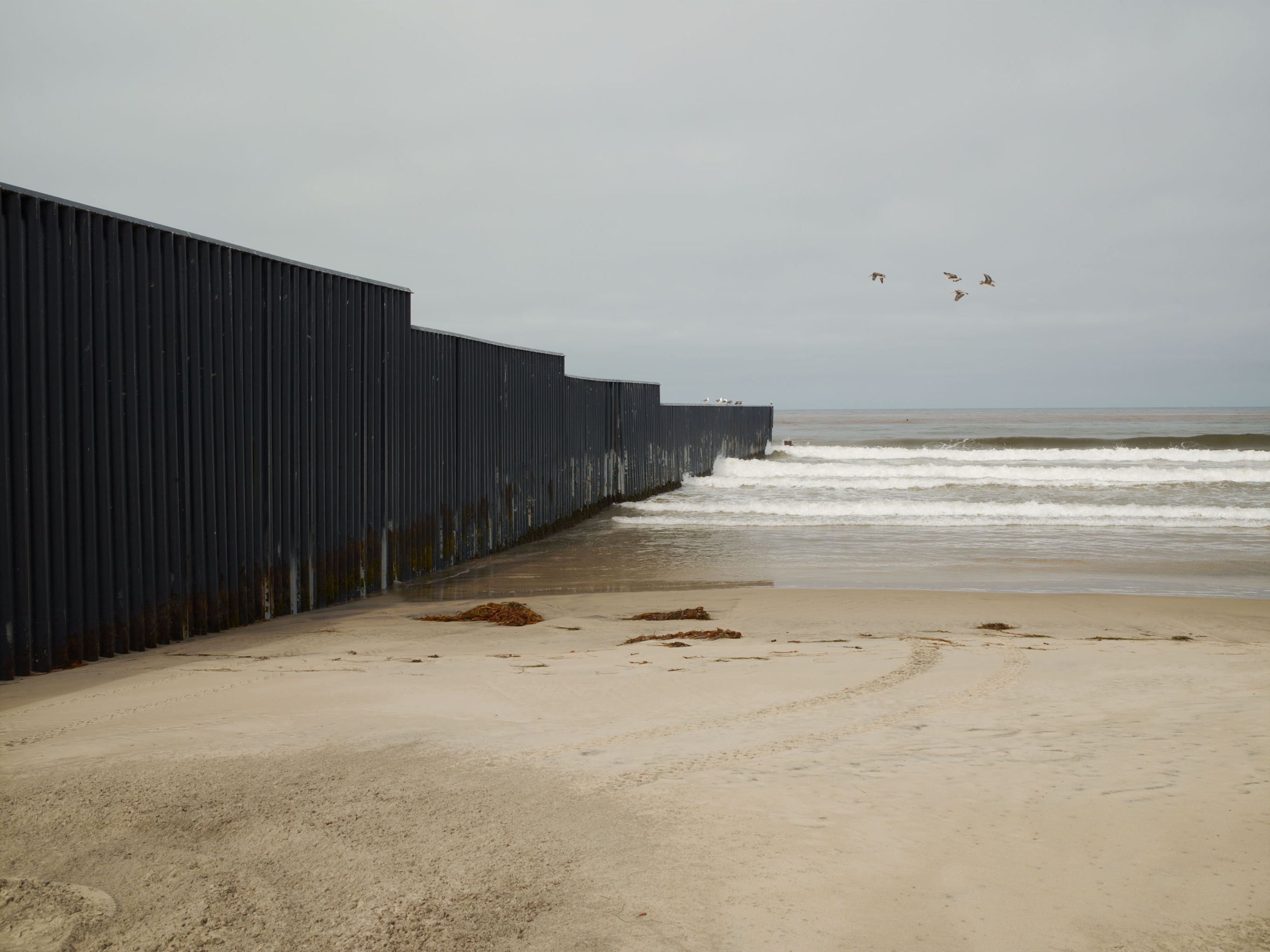 Photos show border walls dividing the U.S. and Mexico