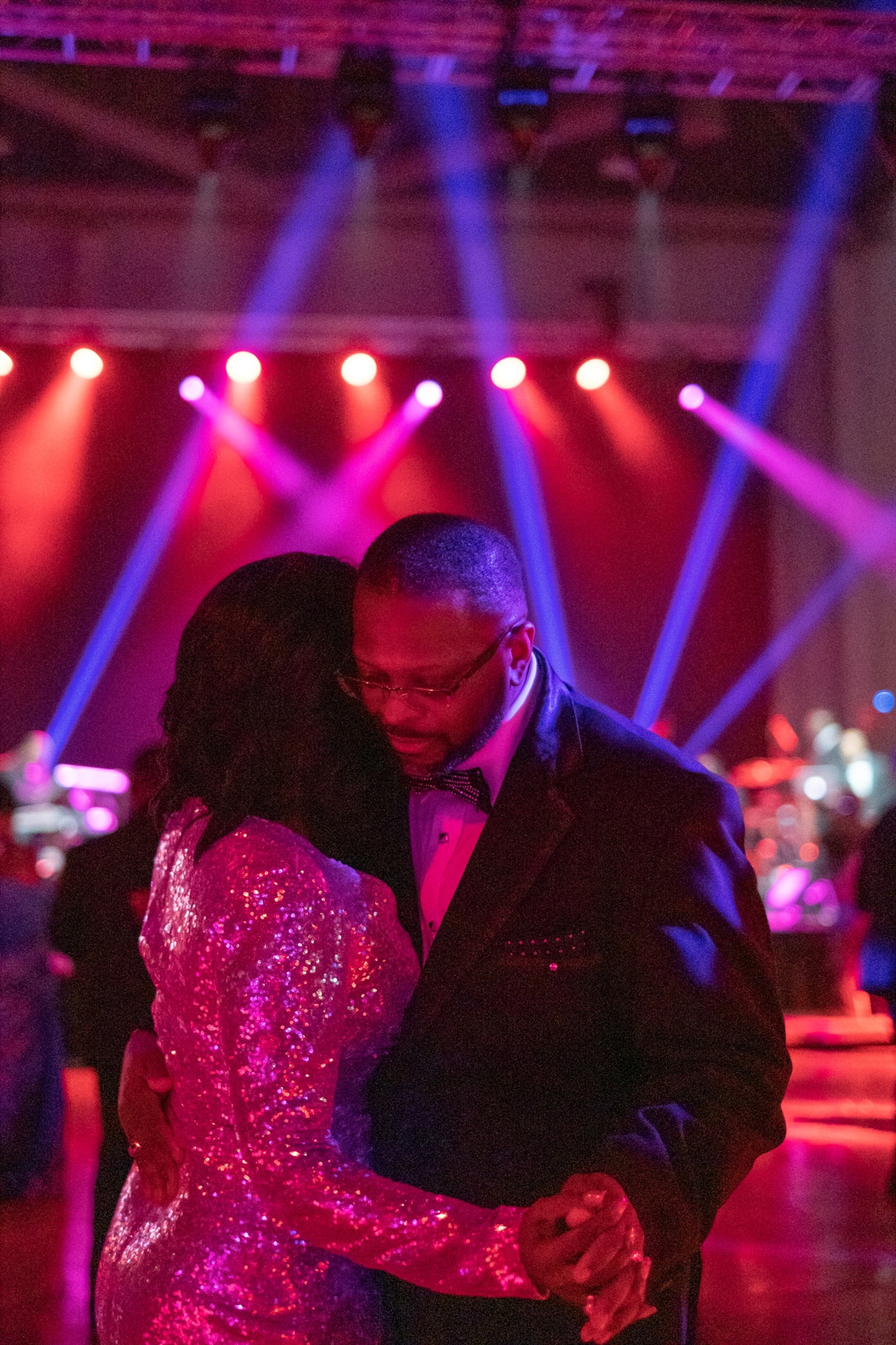 two people dancing amongst red and purple lights