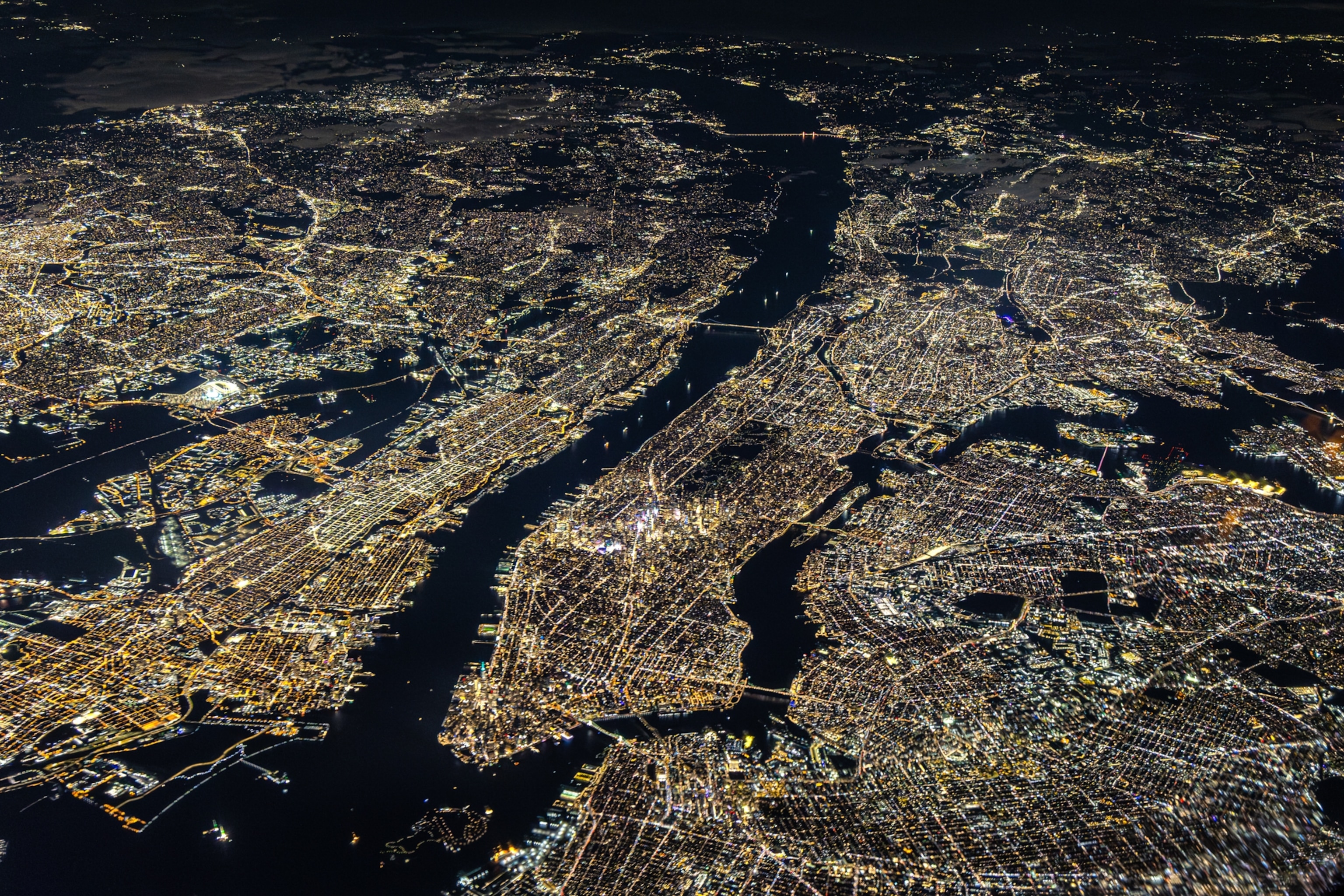 Aerial night view of a New York City with intricate network of streets and rivers
