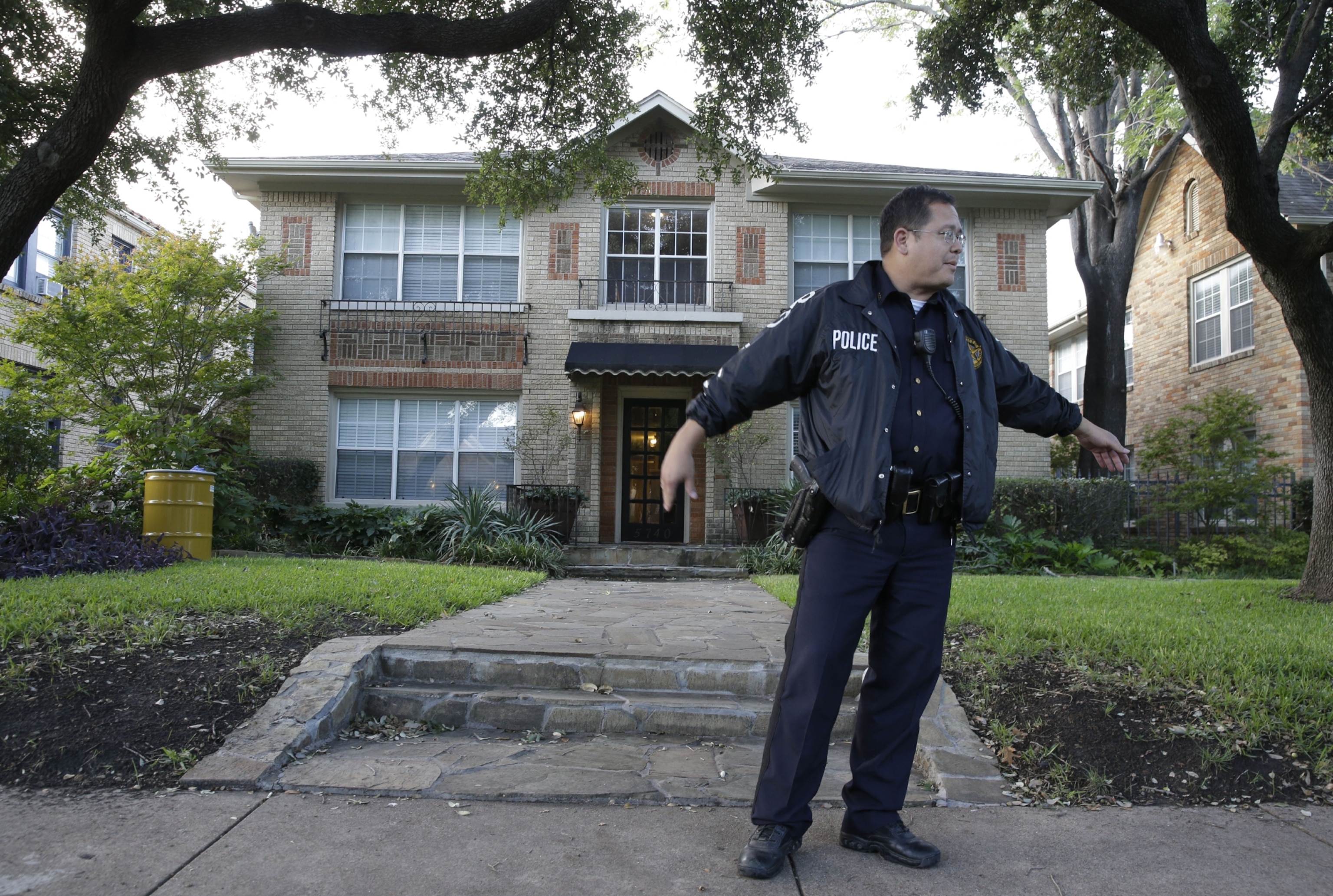 Police stand guard outside the apartment of a hospital worker and a yellow barrel, left, that holds hazardous materials.