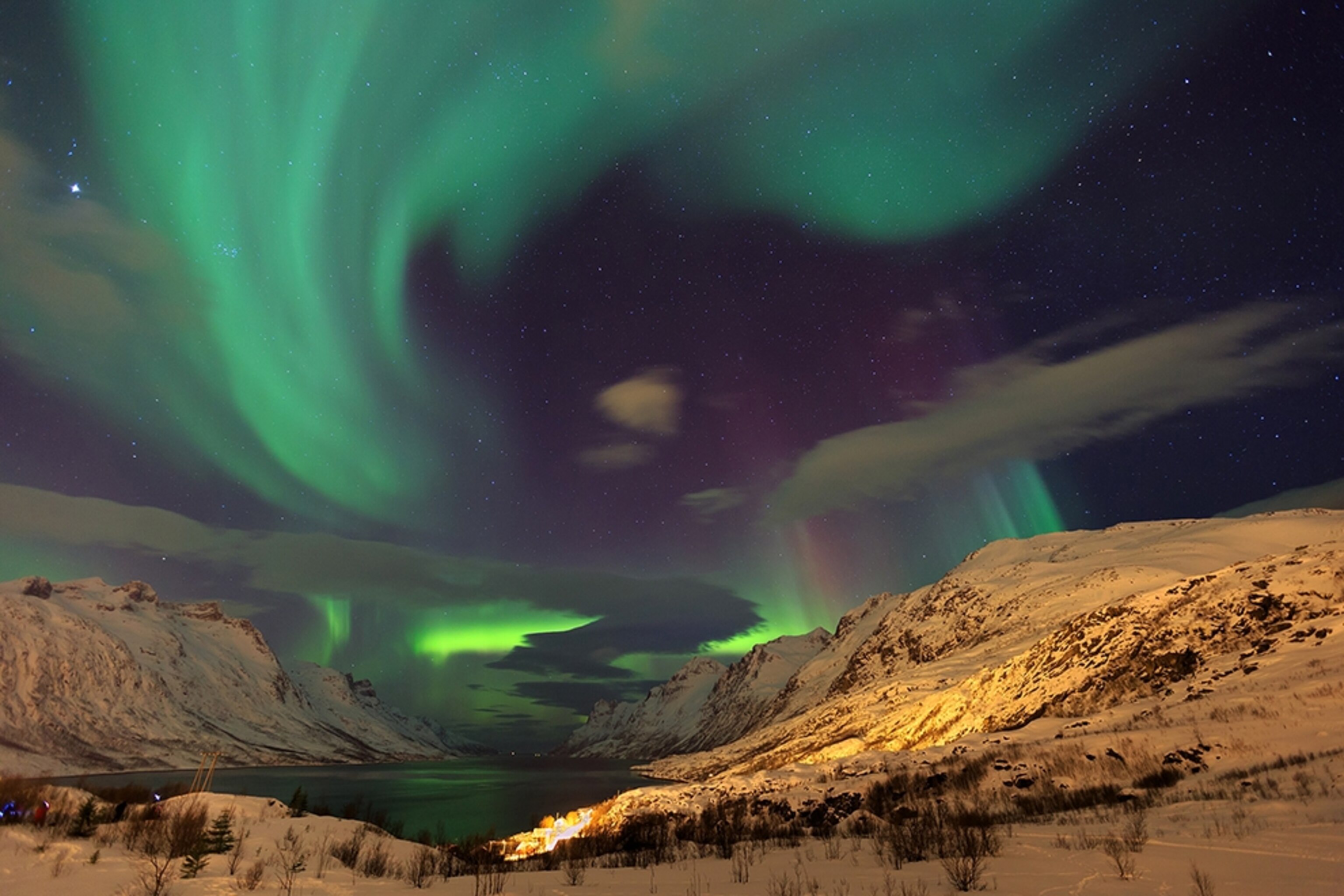 auroras gleaming over Norway's mountains, in a view from north of the Arctic Circle.