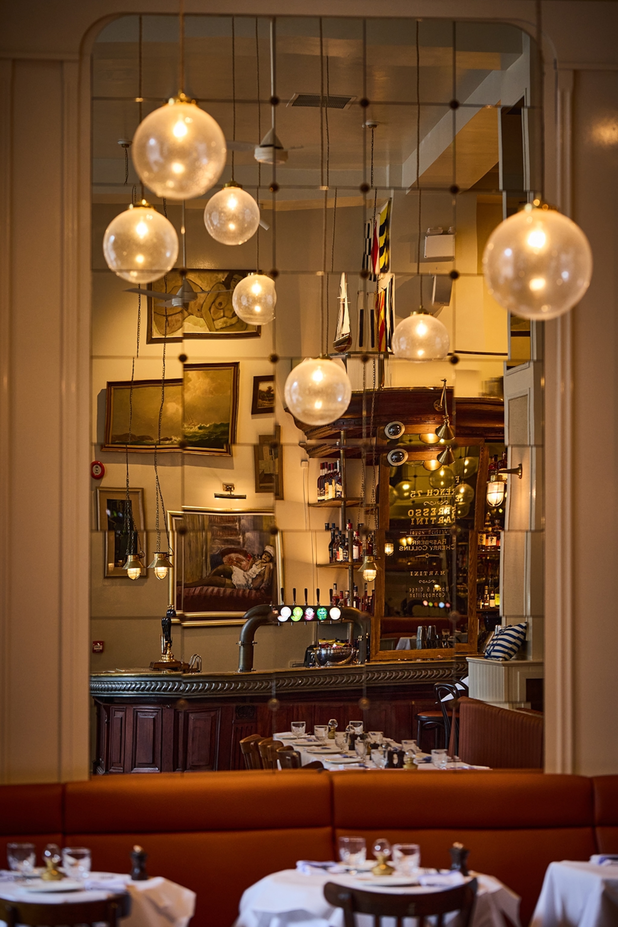 The luxurious interiors of a pub dining room with tall ceilings and globe lights.