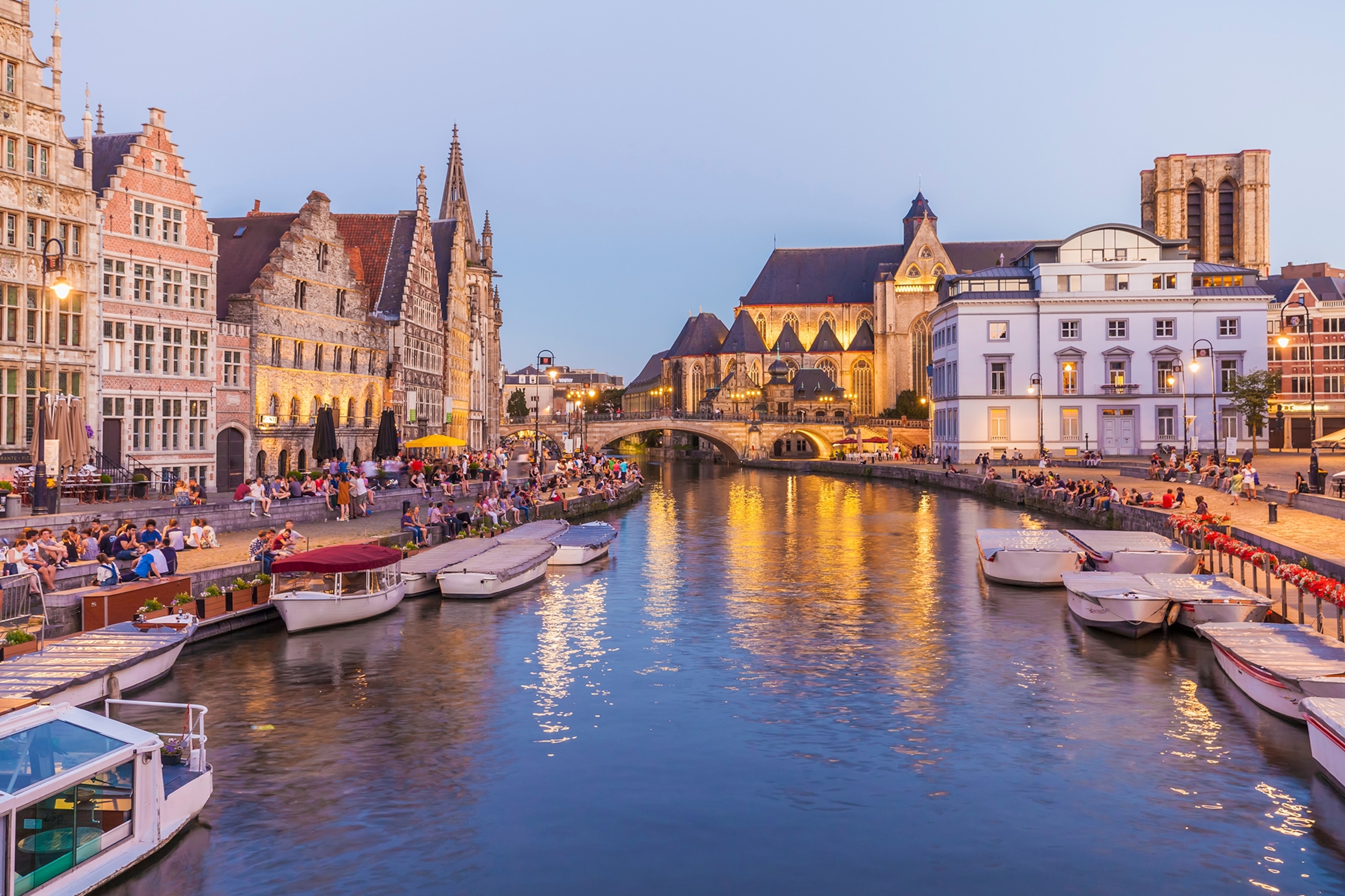 A canal at dusk with romantic houses lining either side and small boats anchored.