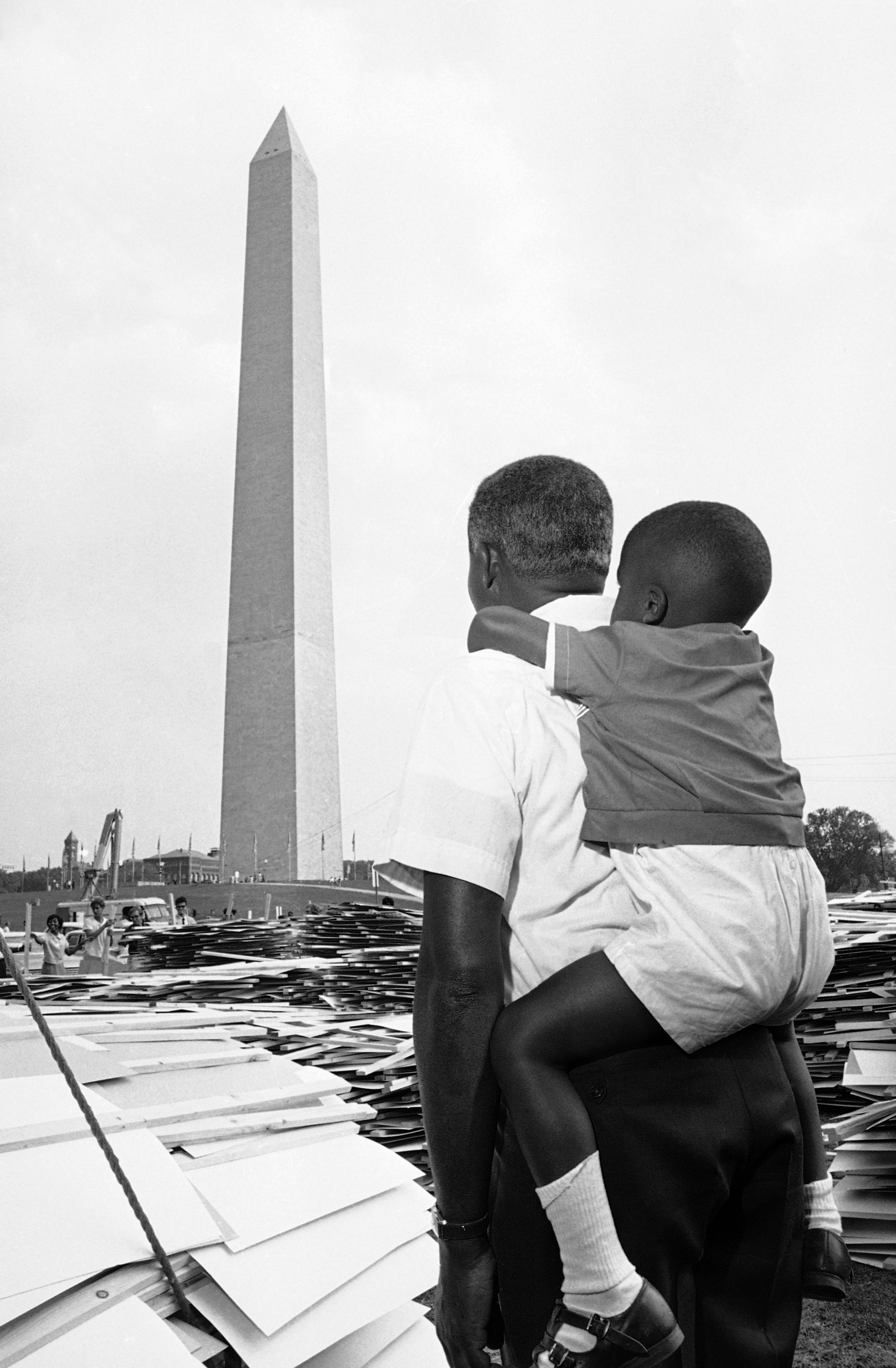Roosevelt Nesmith of Camden, N.J., talks to his three-year-old son, Roosevelt Noel, about the August 28 civil rights March on Washington, August 27, 1963. Between the father and son, and the Washington Monument, is a stack of signs which the marchers, estimated to be more than 100,000, will carry in the demonstration. (AP Photo)