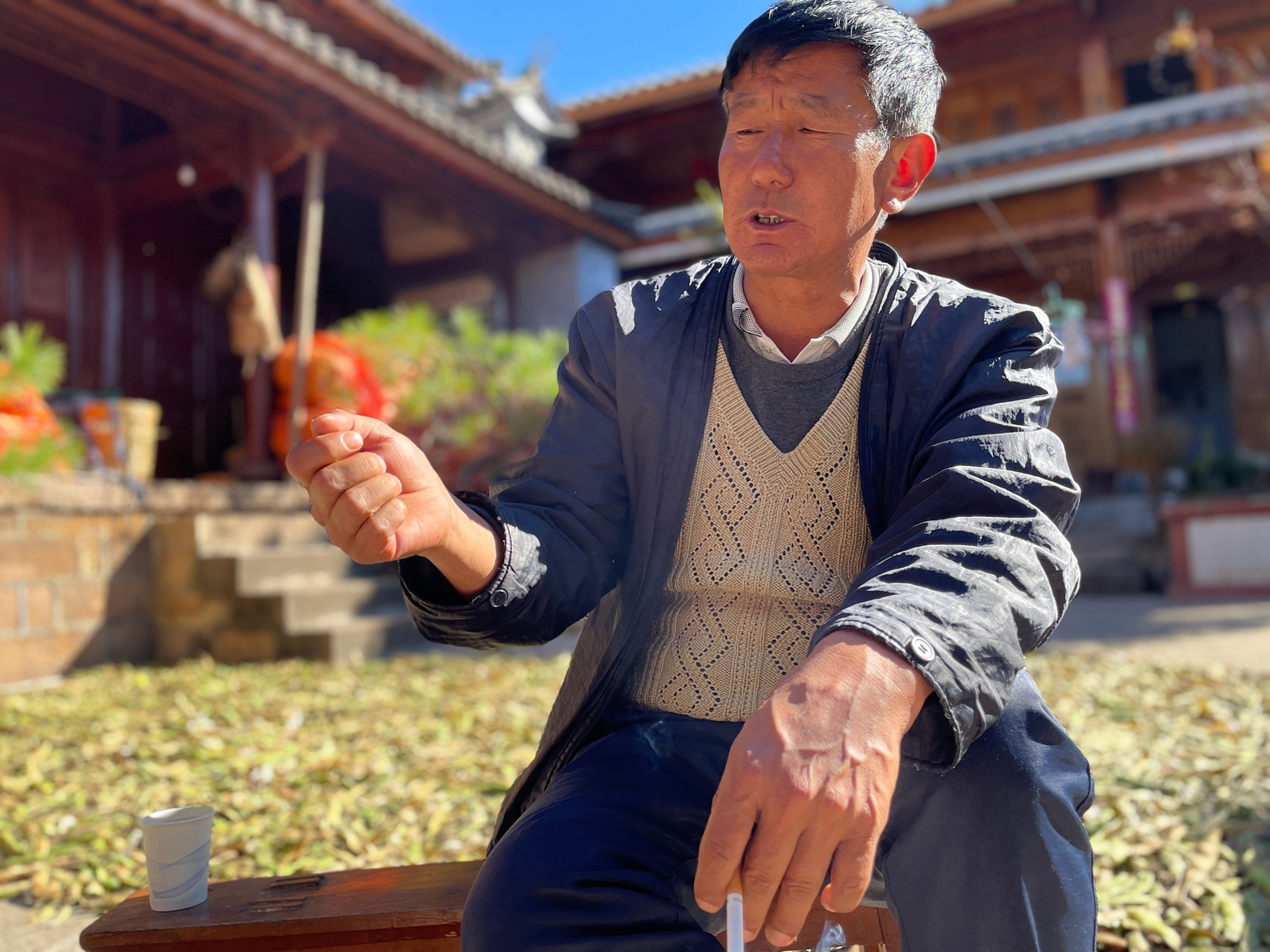 Photo of Li Gen Fan sitting in front of a house