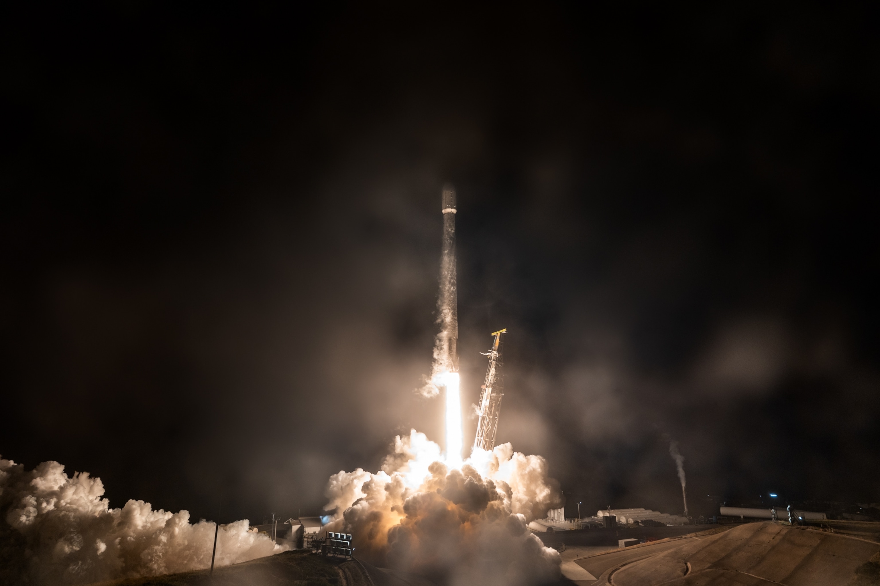 A rocket launching into the night sky, surrounded by bright flames and smoke.