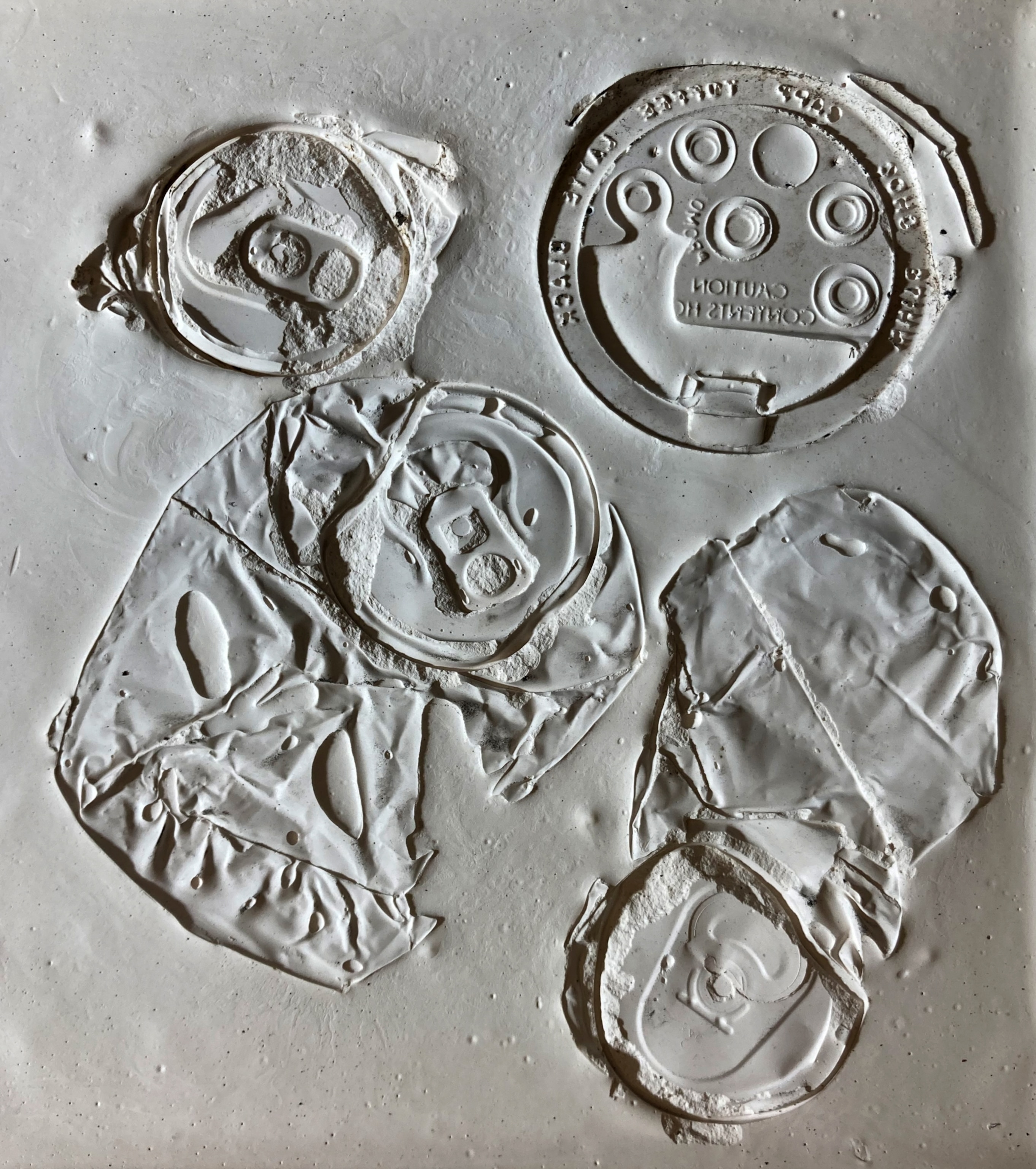 The imprints of soda cans and a plastic lid from a coffee cup left on a mock fossil