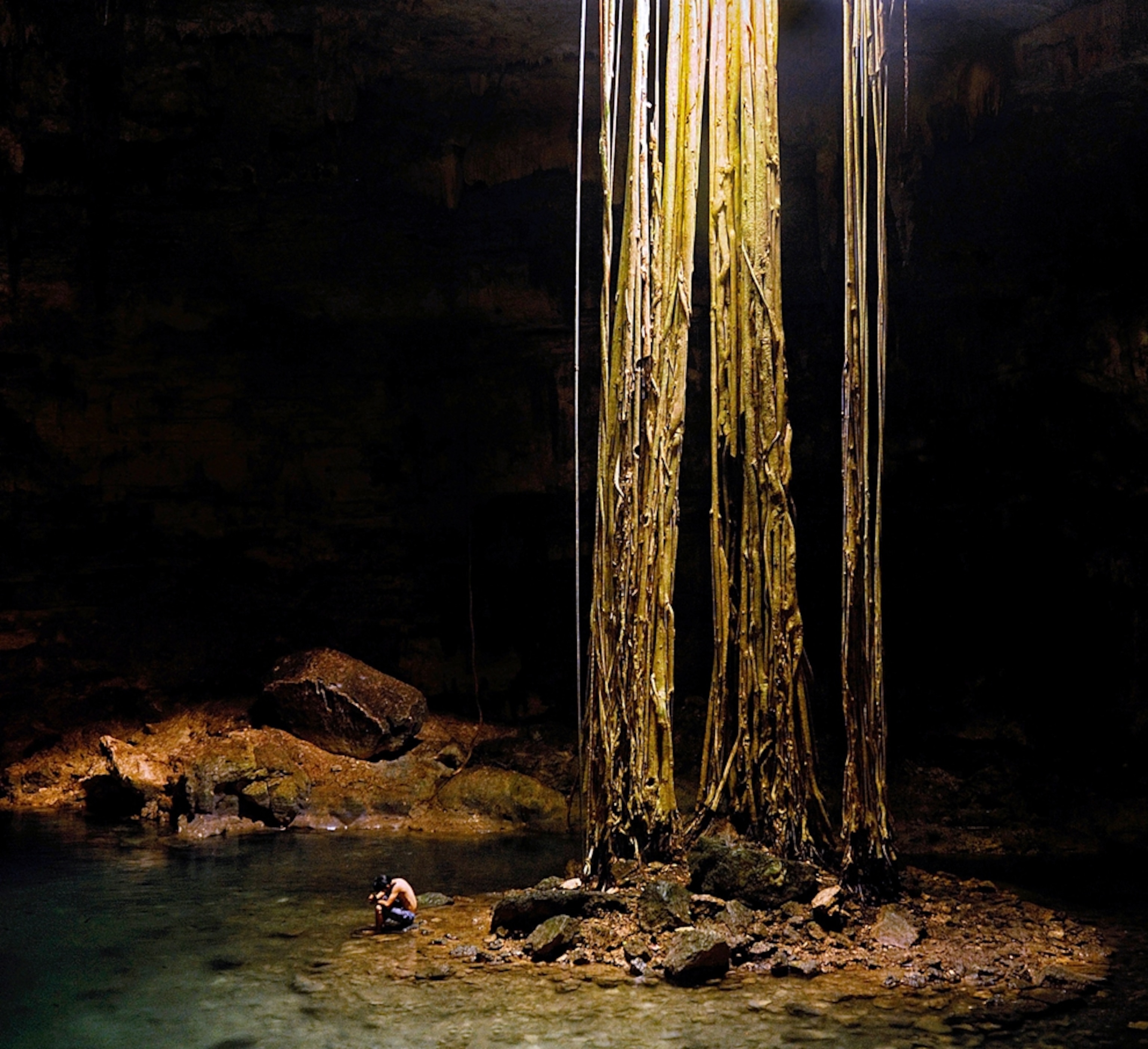 someone kneeling by a cenote, Mexico