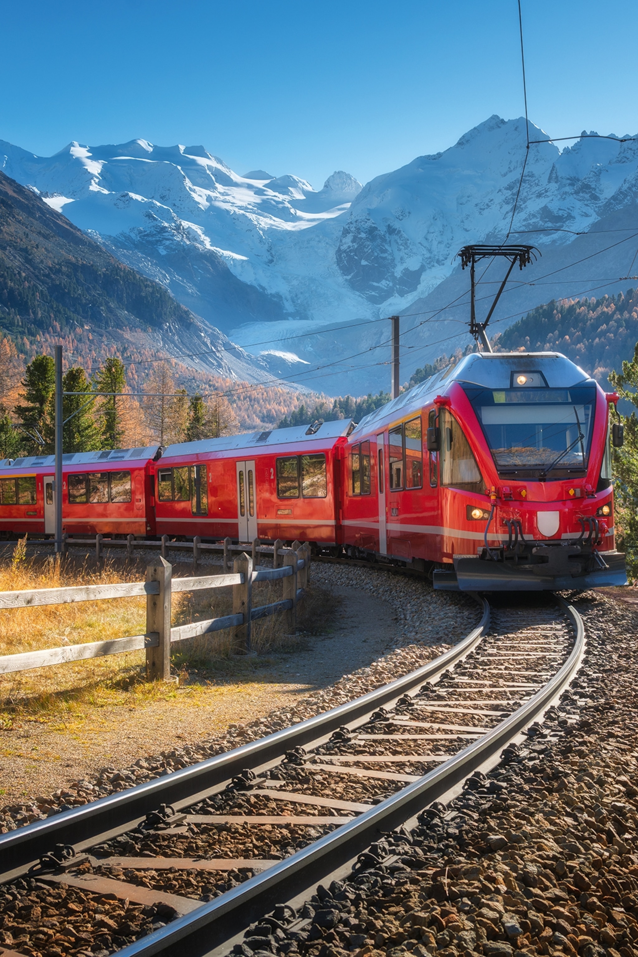An alpine train rolling as a snow-capped mountain landscape unfolds in the background.