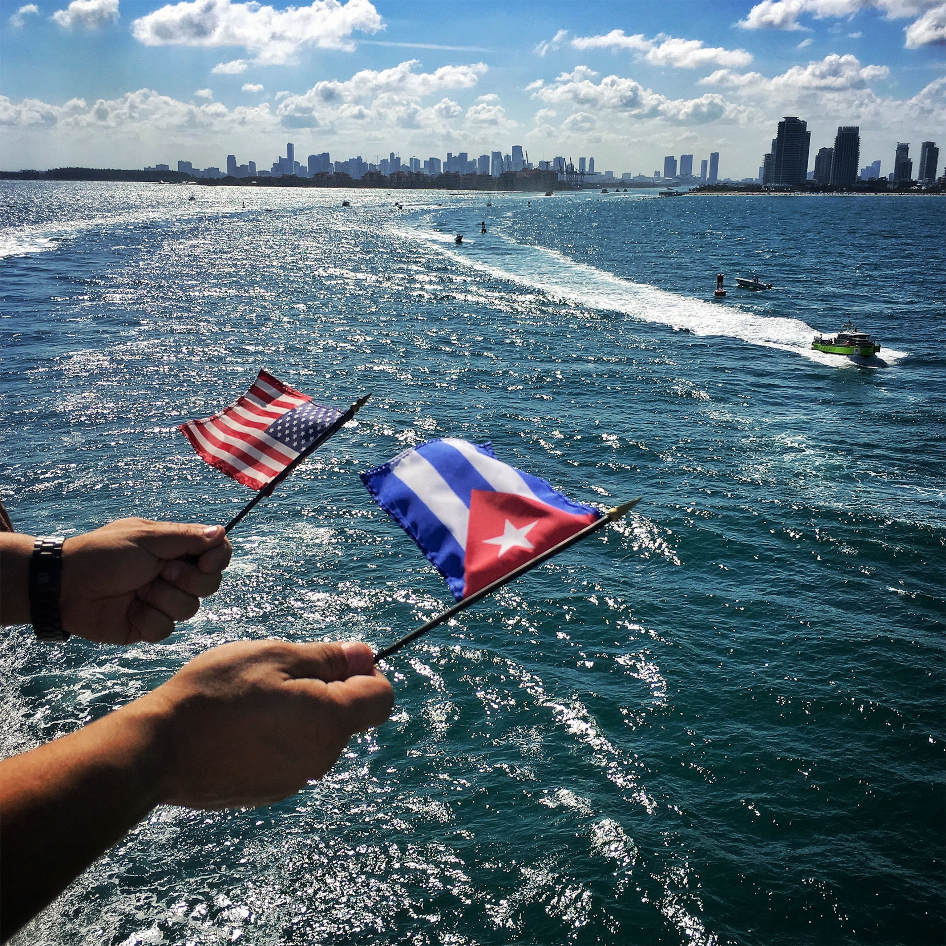 people waving Cuban and American flags on board a ship to Cuba