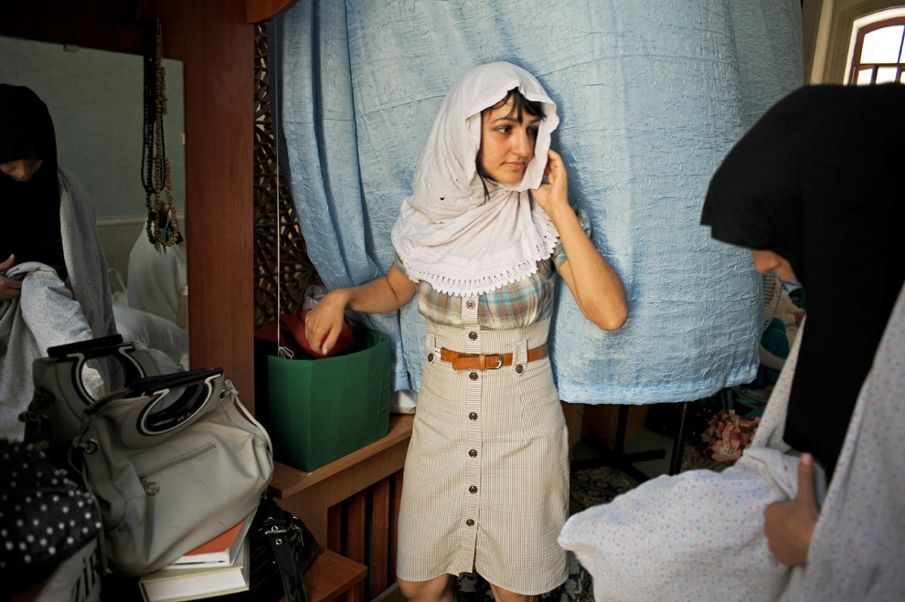 A young woman in secular clothes covers her head before entering mosque in Baku, Azerbaijan.