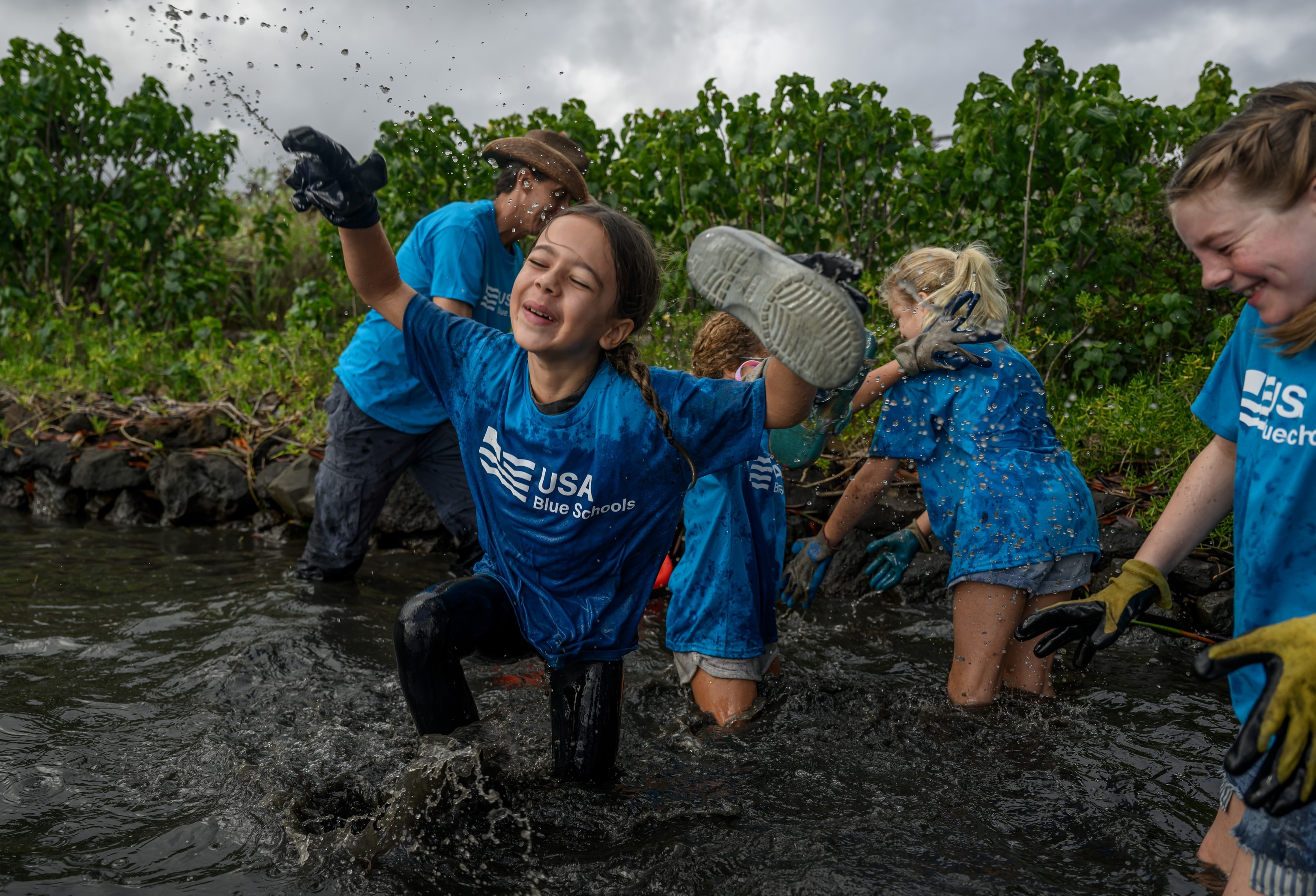 Students from the Blue School Hui frolic in the mud at Waikalua Loko Iʻa