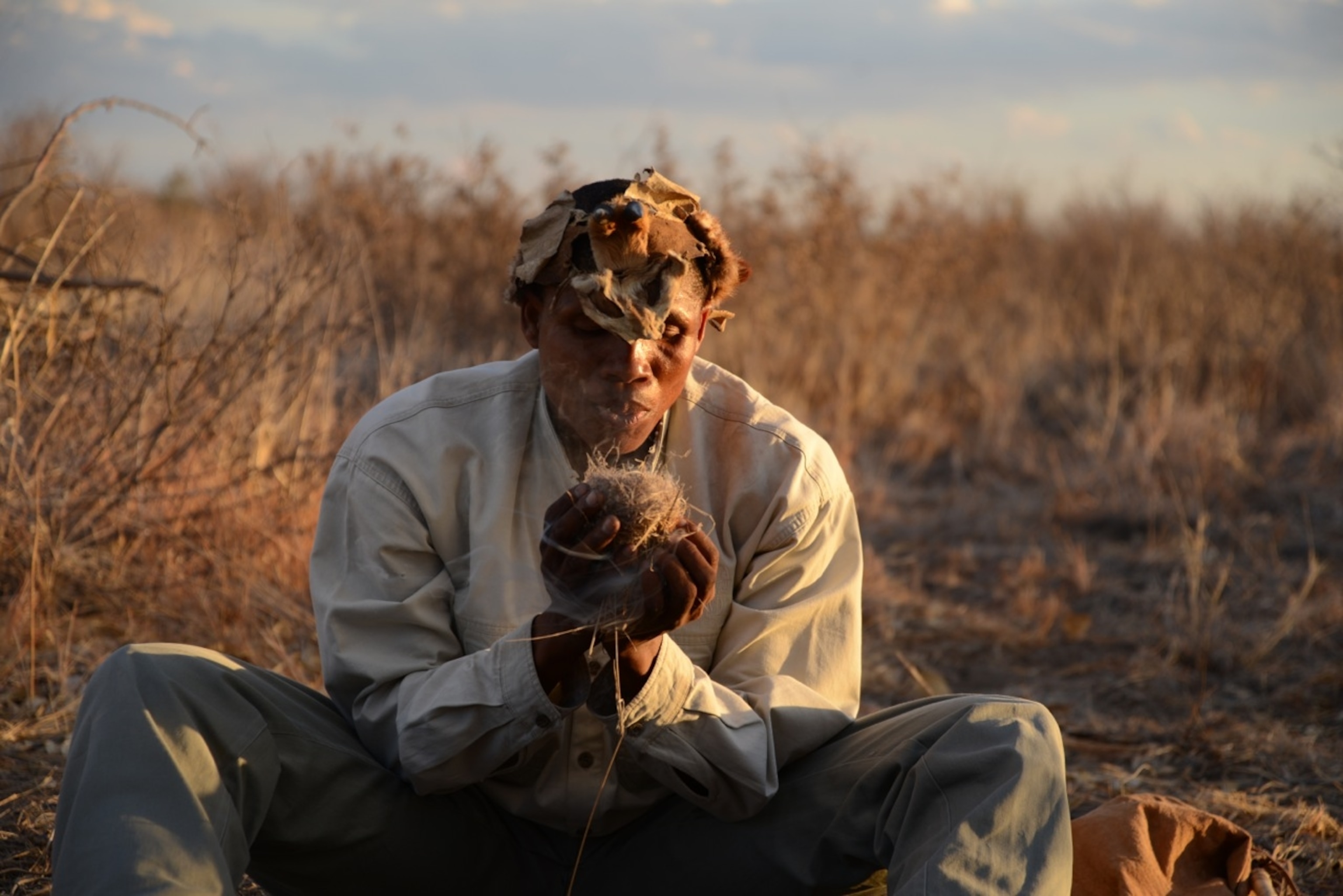 Our San guide Xarama creates fire from two sticks and a bit of Bushman Love Grass (Photo by Andrew Evans, National Geographic)