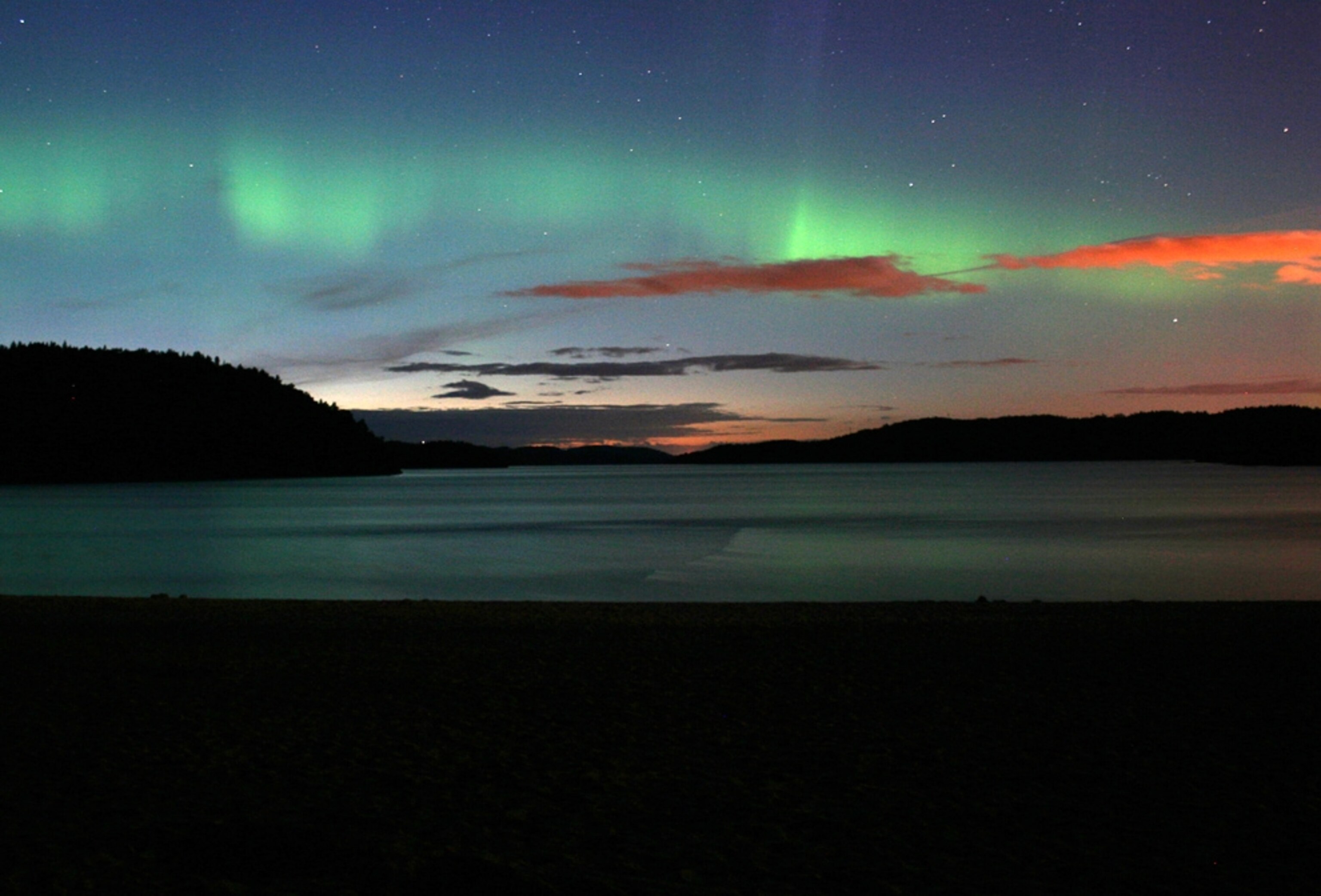 northern lights, or an aurora borealis, over a beach in Grimstad, Norway.