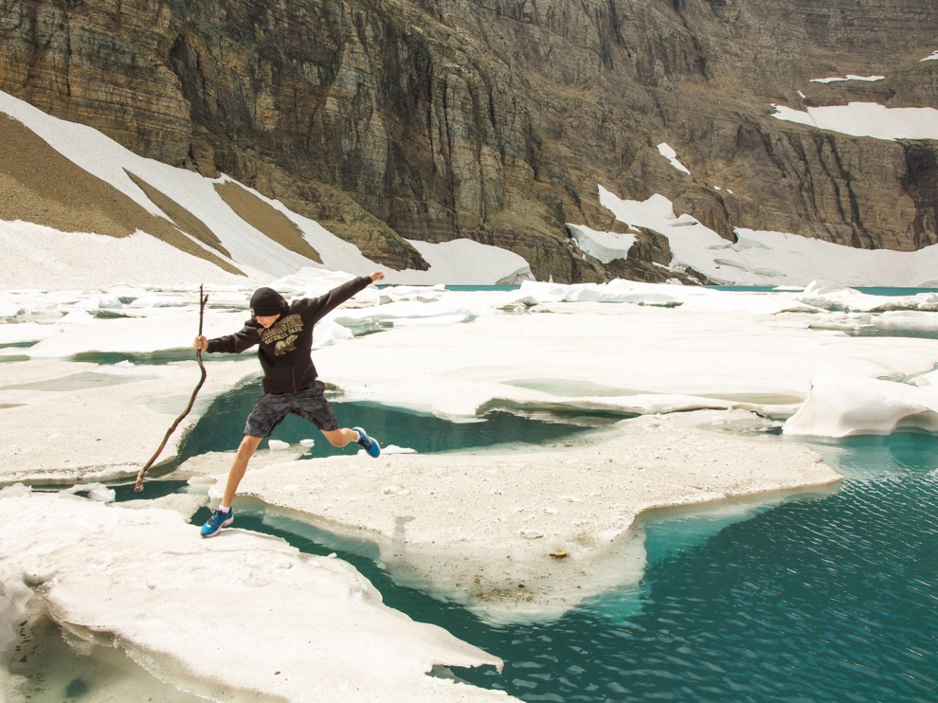 a young man jumping on icebergs on Iceberg Lake, Glacier National Park