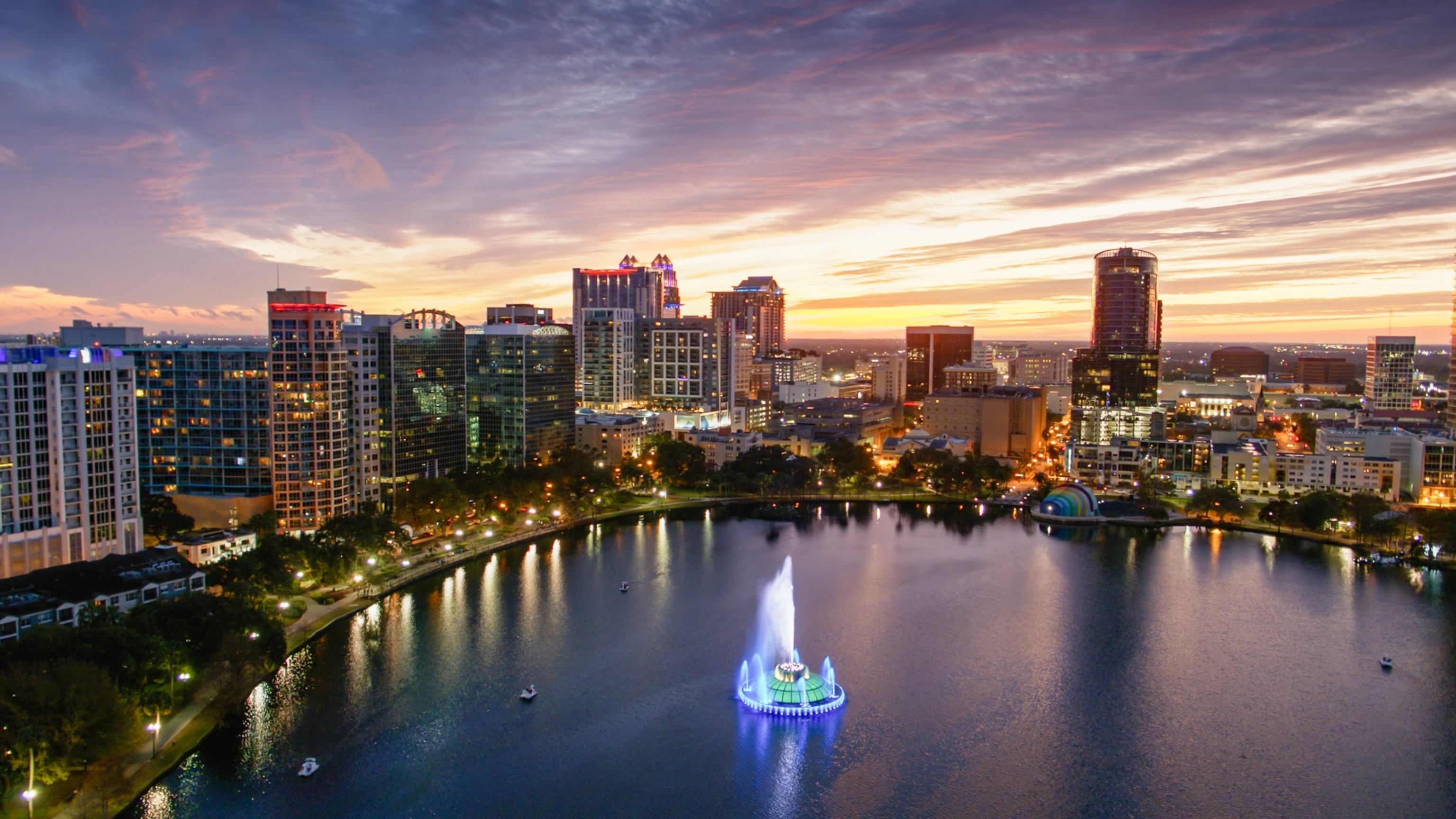 Drone shot of Downtown Orlando at sunset, taken from over Lake Eola looking down on the Linton E. Allen Memorial Fountain.