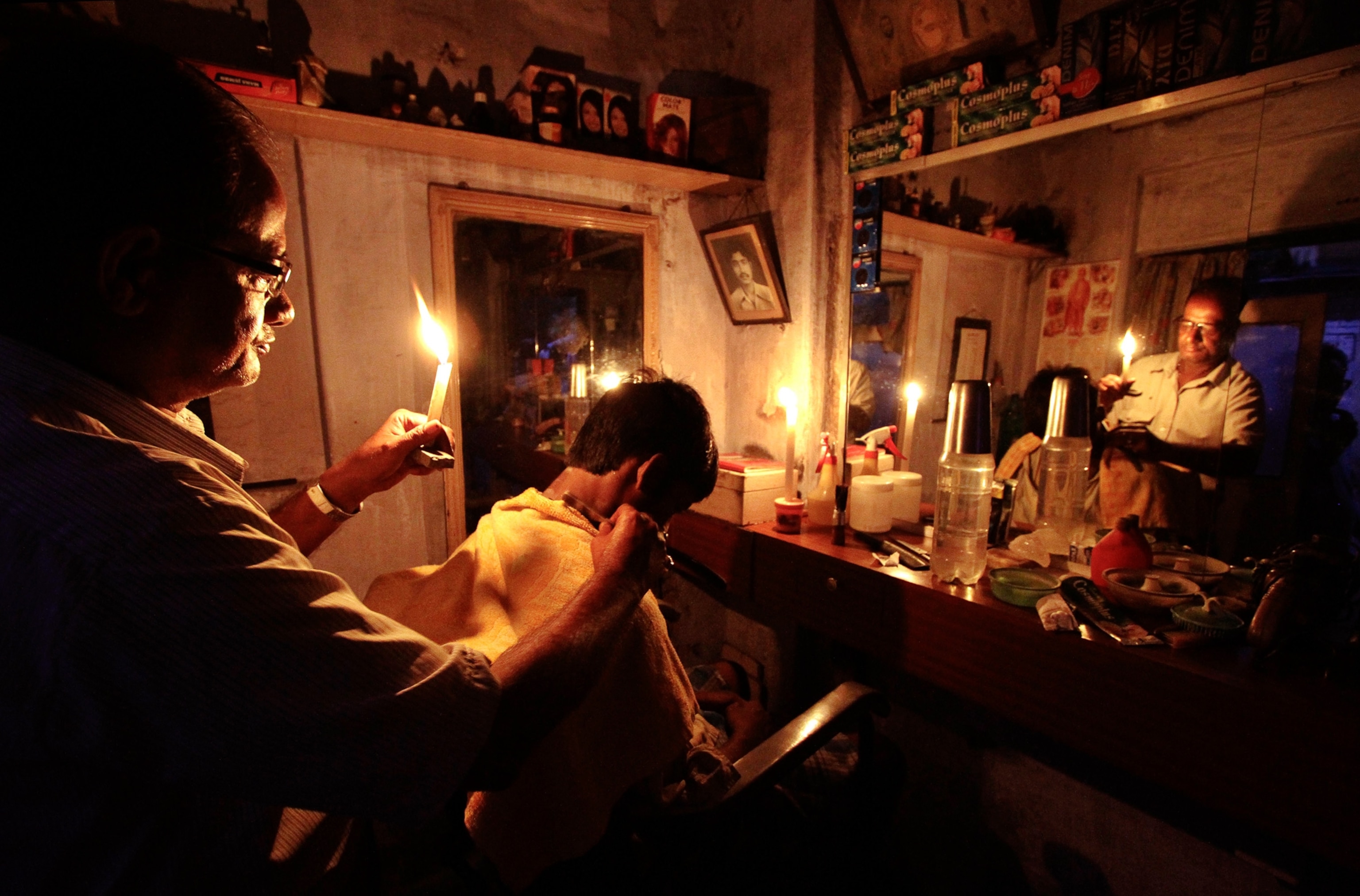 India power outage picture: a barber cutting hair by candlelight in Kolkata (Calcutta) during blackout