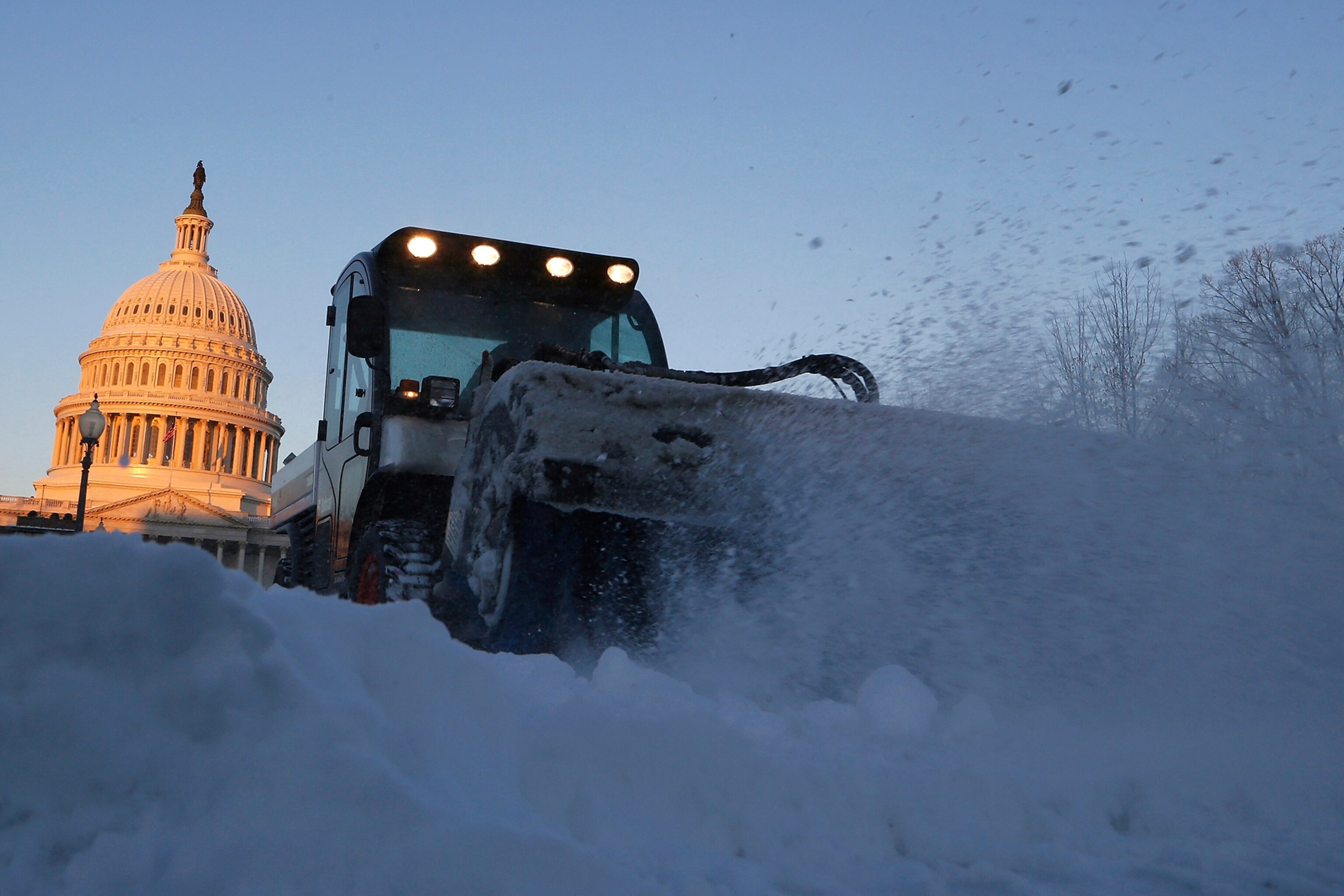 A woman walks outside of an office building as snow falls, Tuesday, Jan. 21, 2014, in Baltimore. Thousands of flights were canceled, students got an extra day off from school or were being sent home early, and the federal government closed its offices in the Washington area Tuesday as another winter storm bore down on the Mid-Atlantic and Northeast.