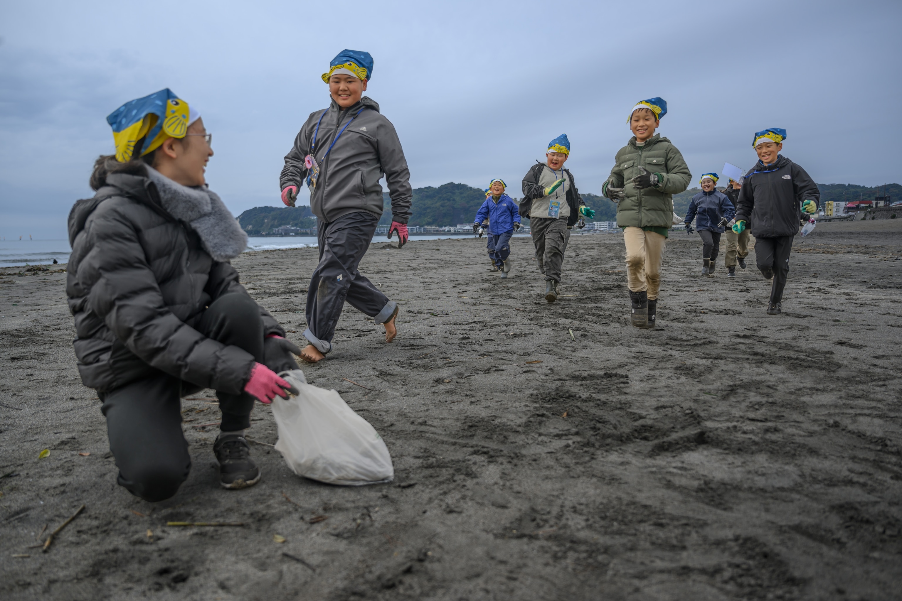 A cohort of Sakana-kun Ocean Explorers gather to frolic in the sand, get wet and remove plastic trash.