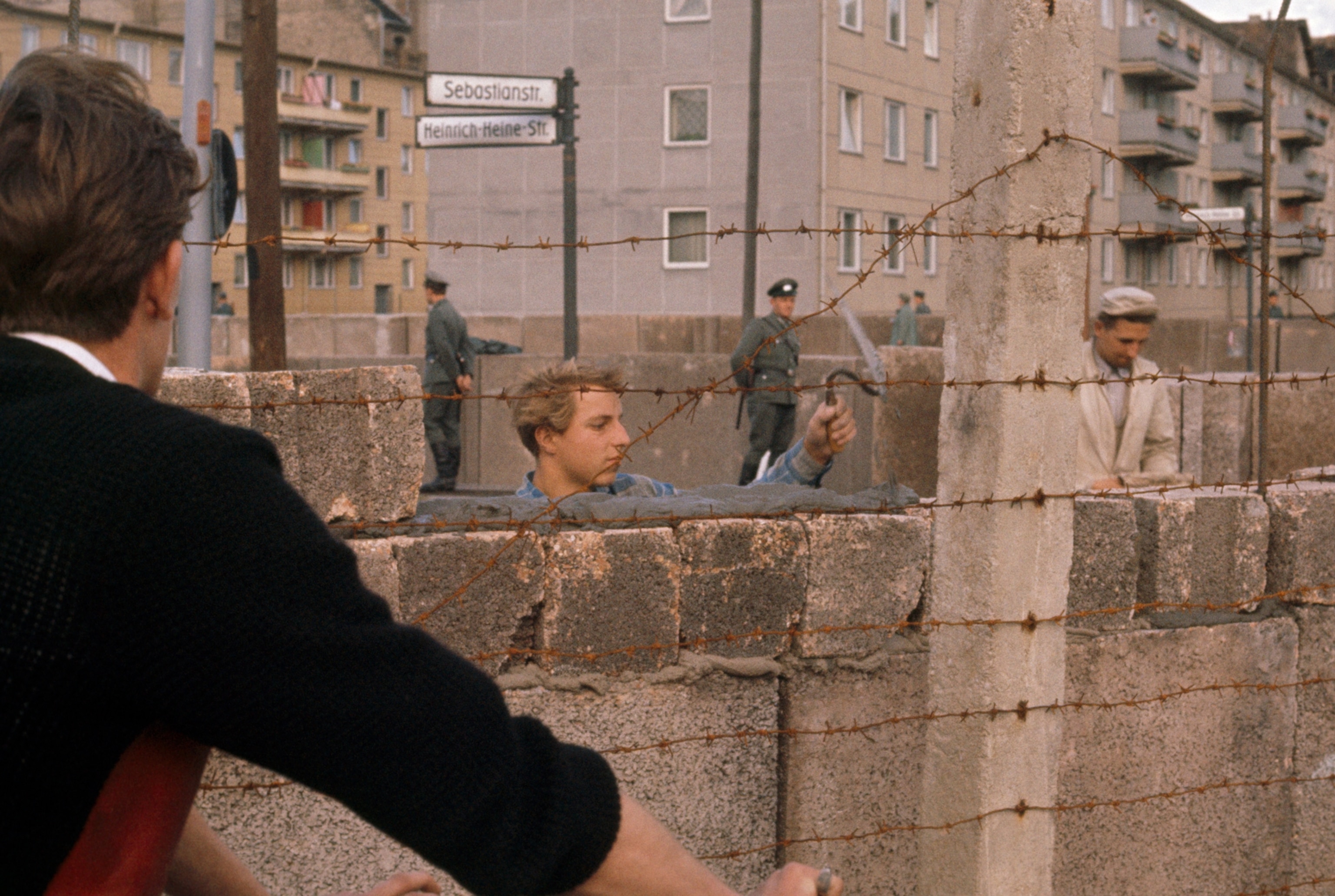 Under guard by Vopos, Mason Wall themselves in mistrusting East Berliners, the Communists imported bricklayers from Saxony to build the barrier that stretches for 30 miles across the city. The wall divides families and friends and keeps workers from their jobs. West Berliners sometimes refer to it as "Ulbricht's Chinese wall" after East German boss Walter Ulbricht.