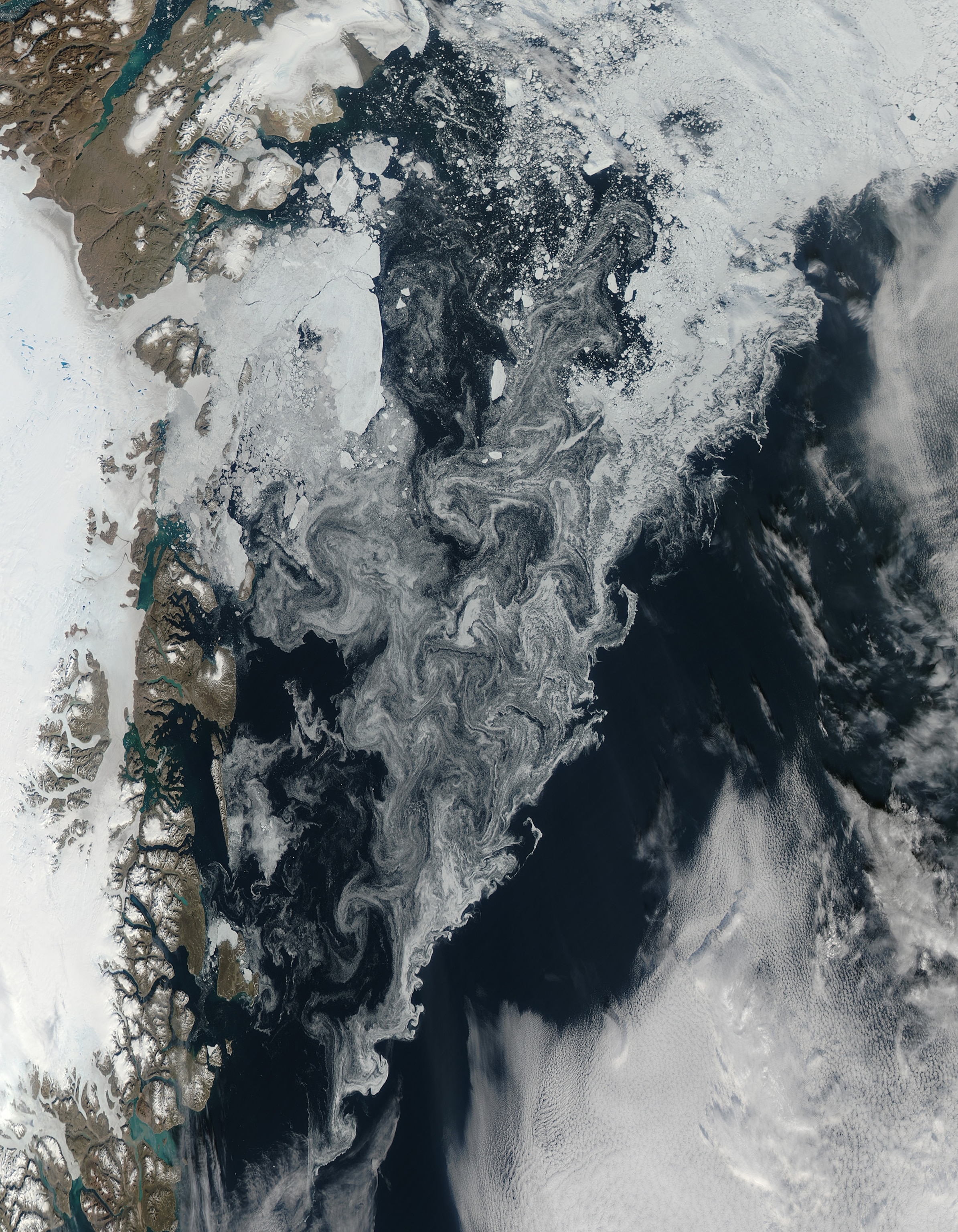 hick tongues of glacial ice stretch over the fjords on the Greenland coast at image left.