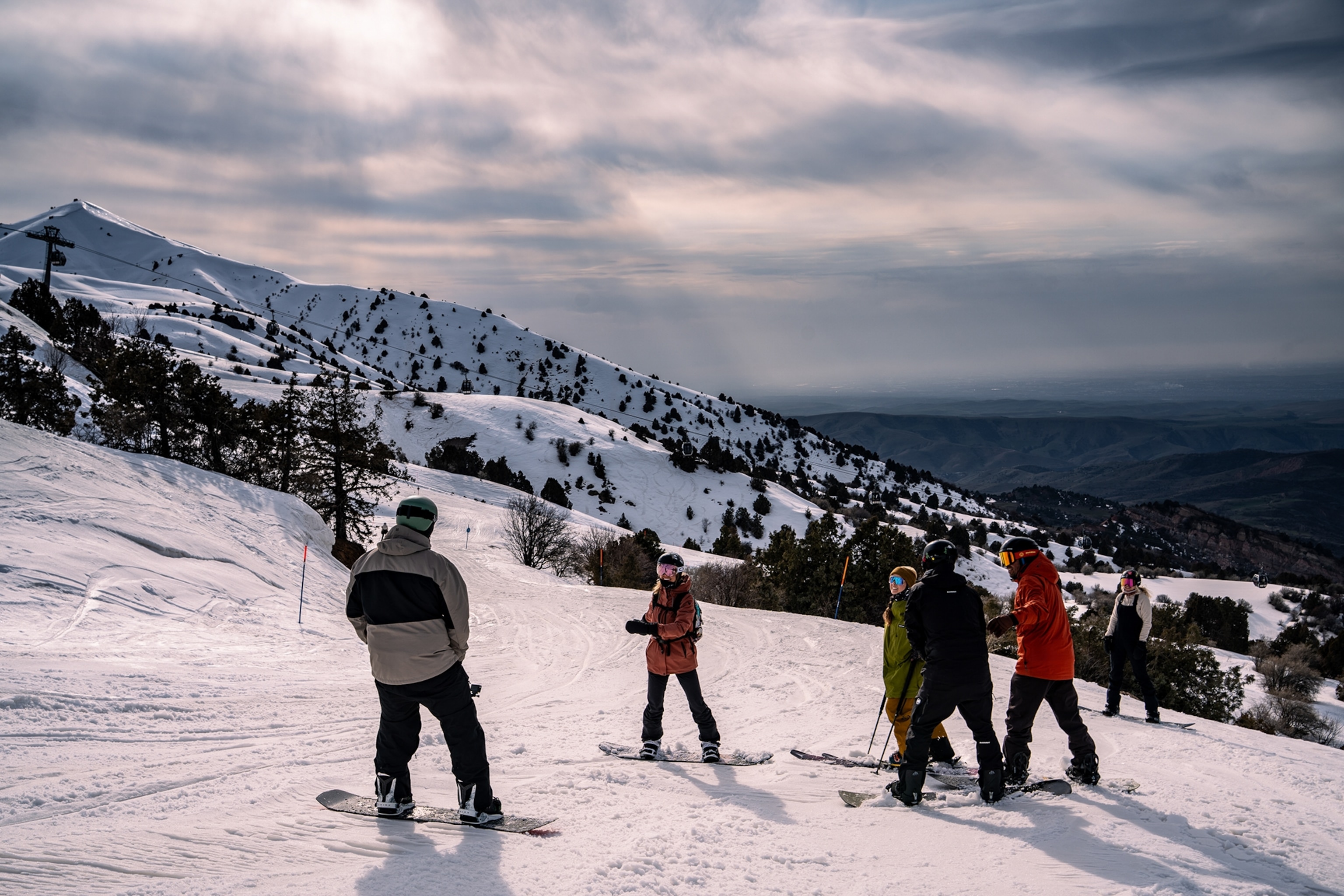 A group of skiers and snowboarders catching up on the side of a piste.