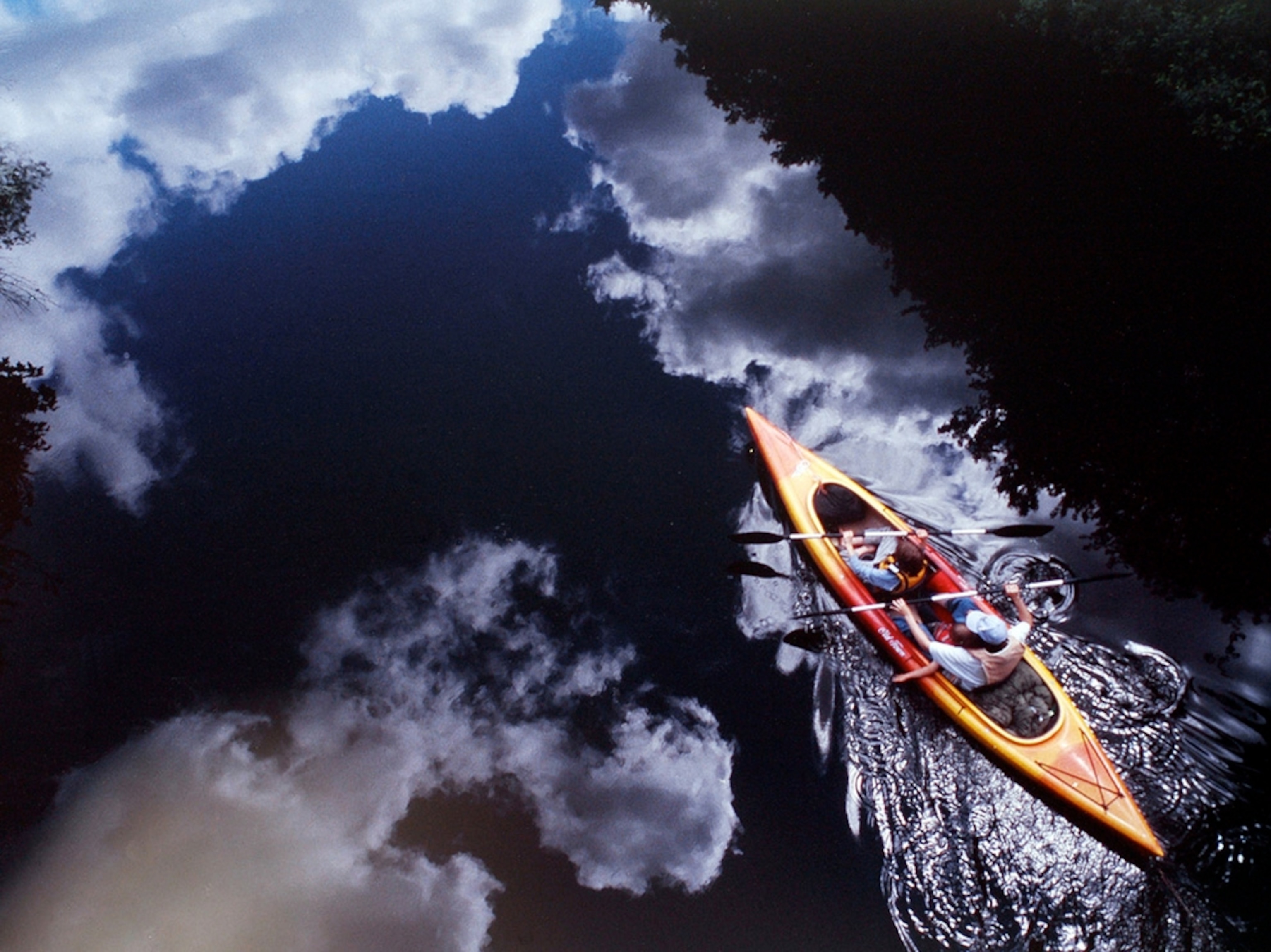 Reflections on lake as kayaker passes