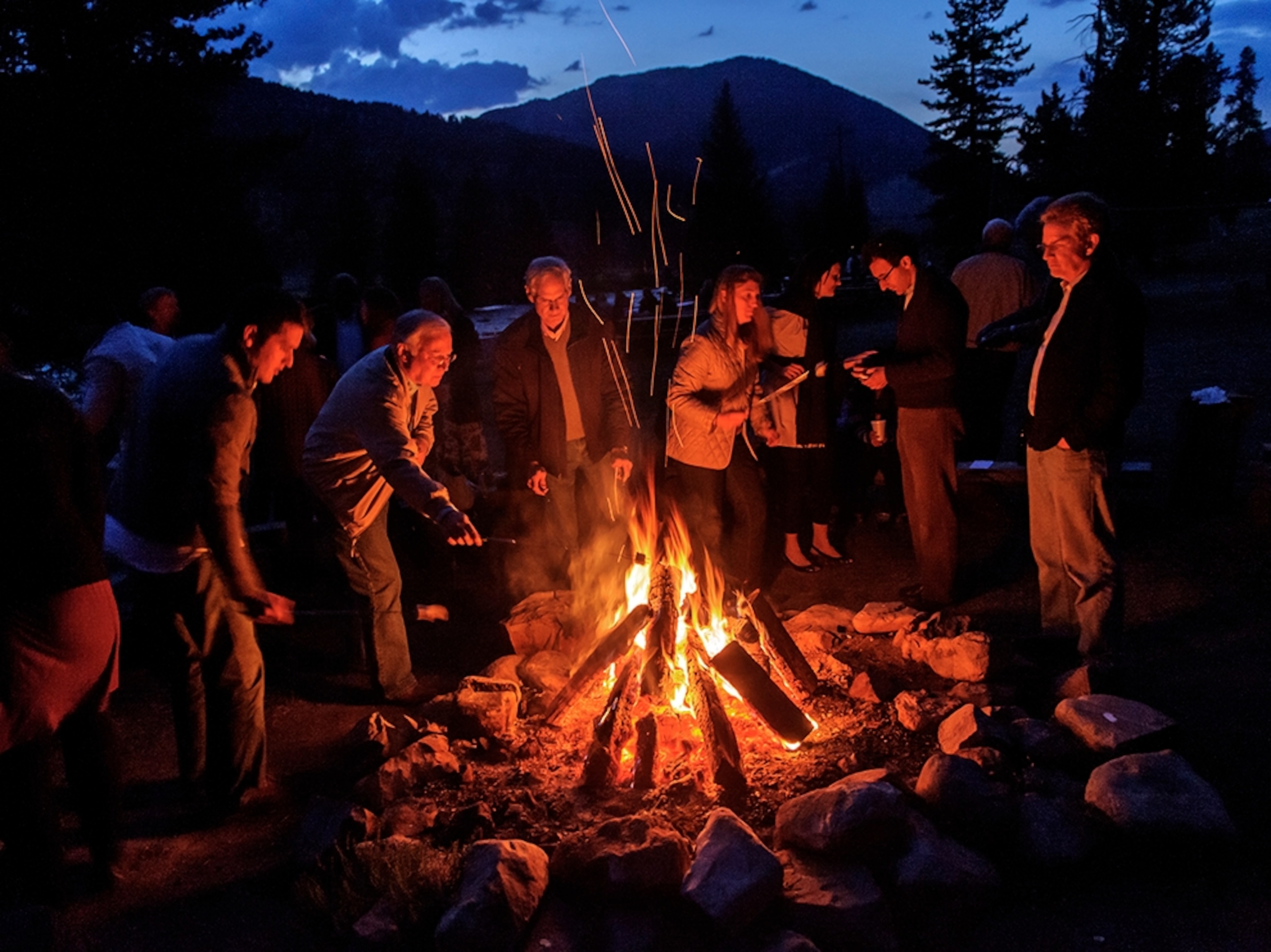 a group of people standing around a campfire at 320 Guest Ranch