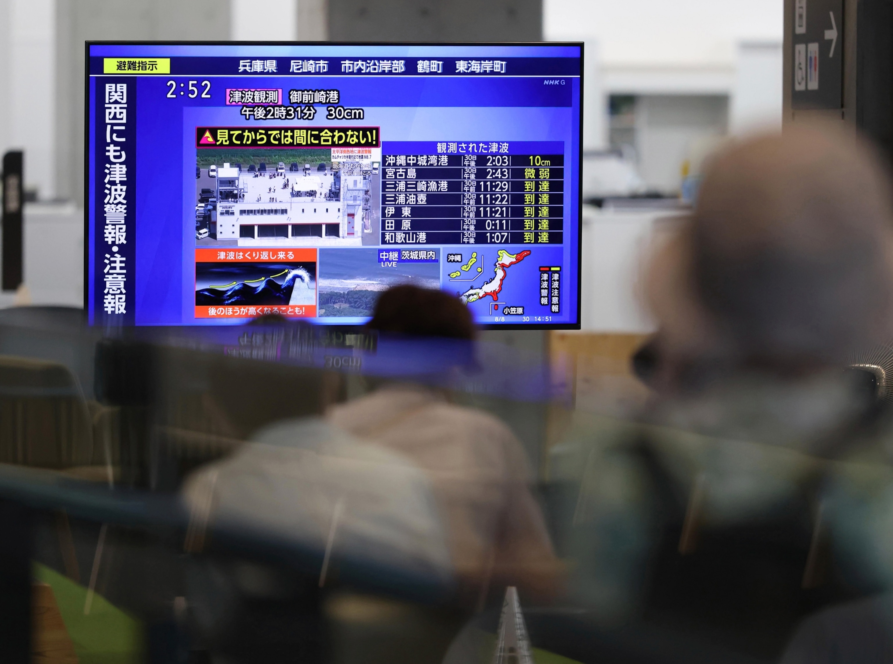 Residents at City Hall, which is being used as a tsunami shelter, watching a TV which is reporting on the tsunami warning.