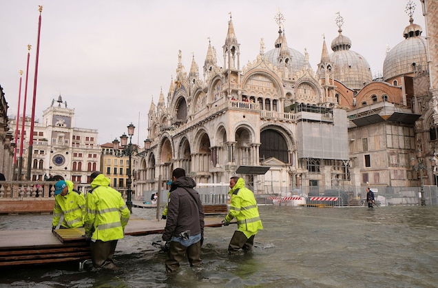 Workers prepare a temporary catwalk in a flooded St. Mark's Square.