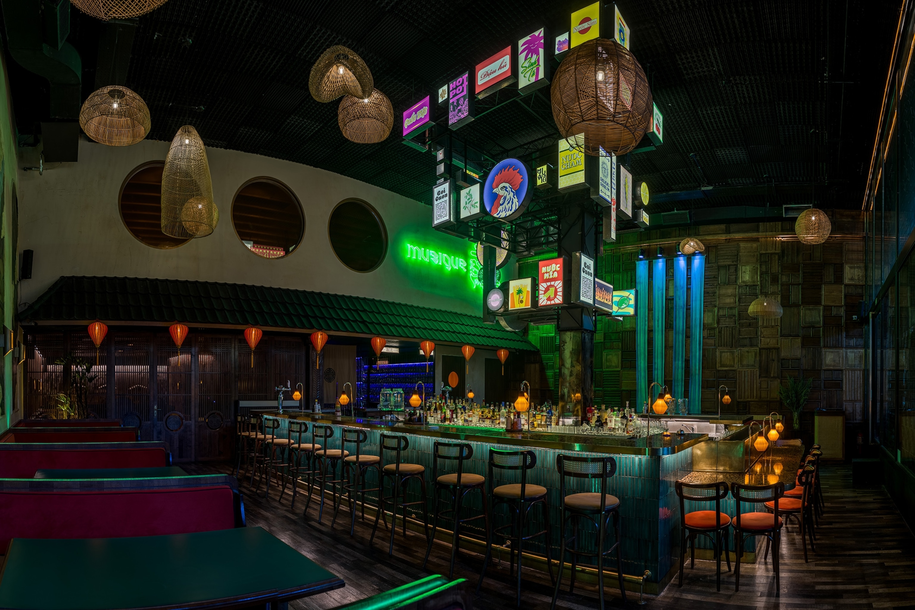 A modern bar island in a big room decorated with neon lights and lit-up signs.