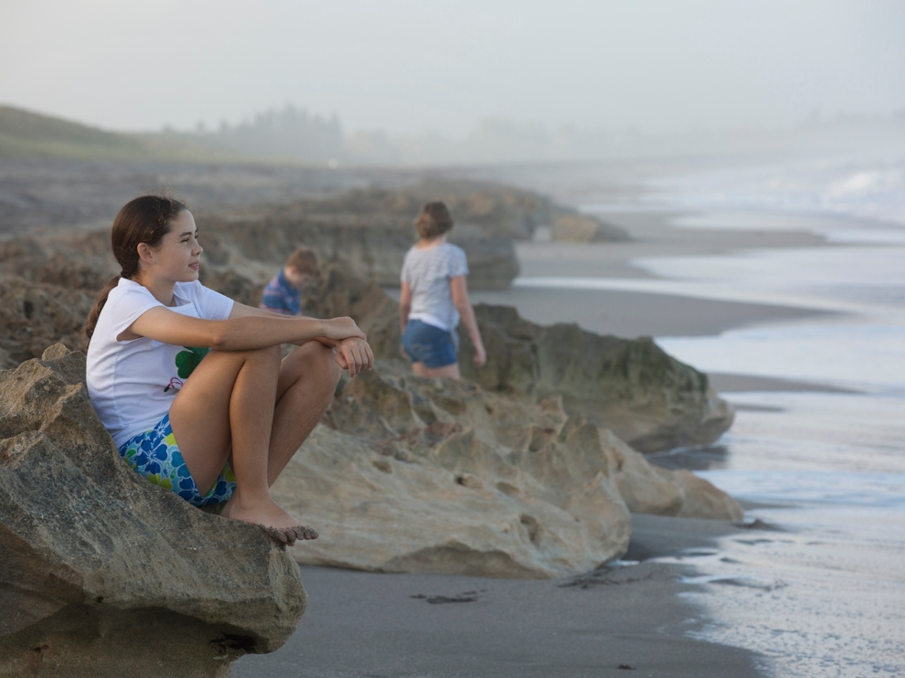 a young girl sitting at Blowing Rocks Beach in Florida