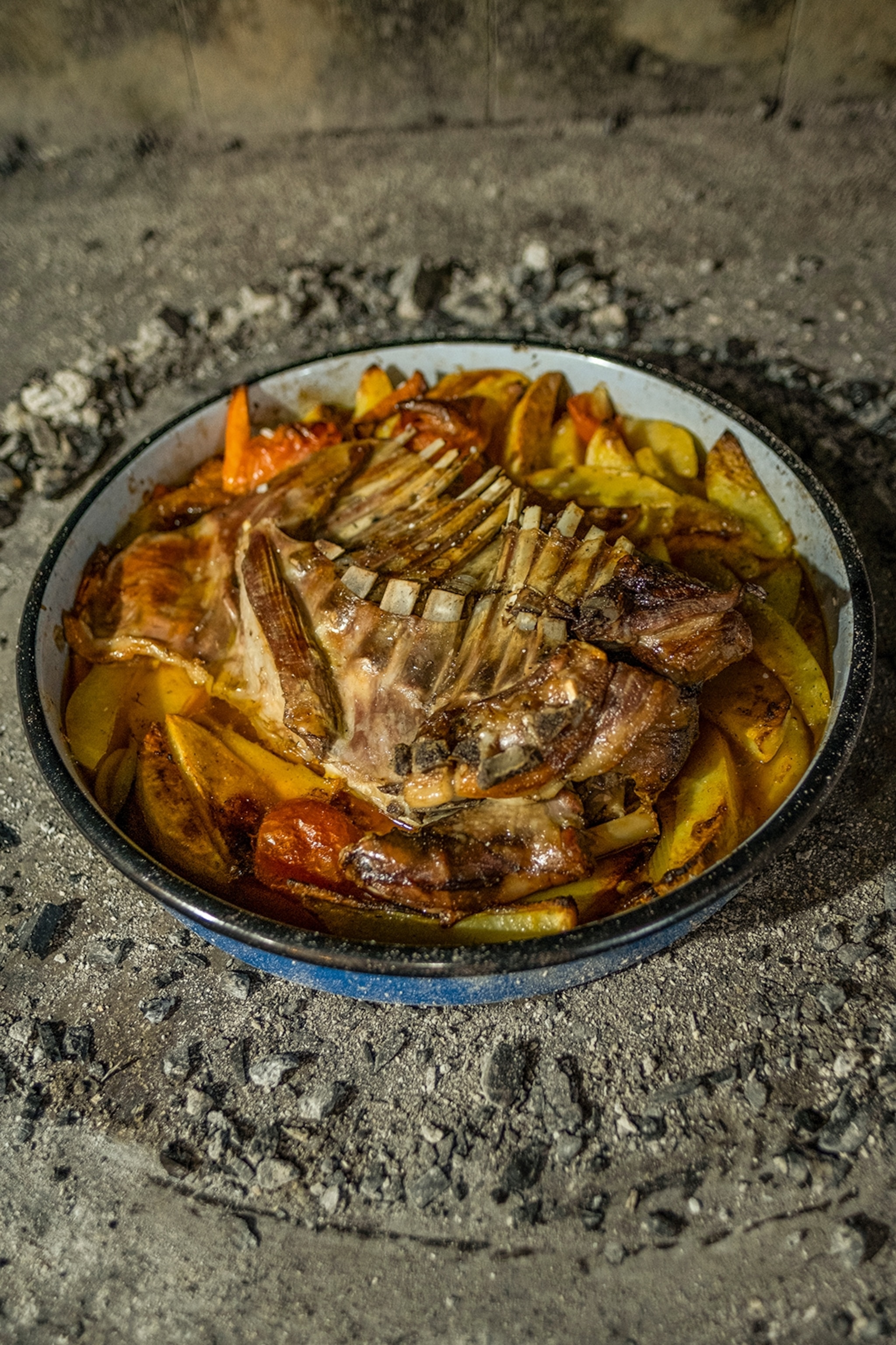 An iron tray with roasted lamb rack and potatoes.