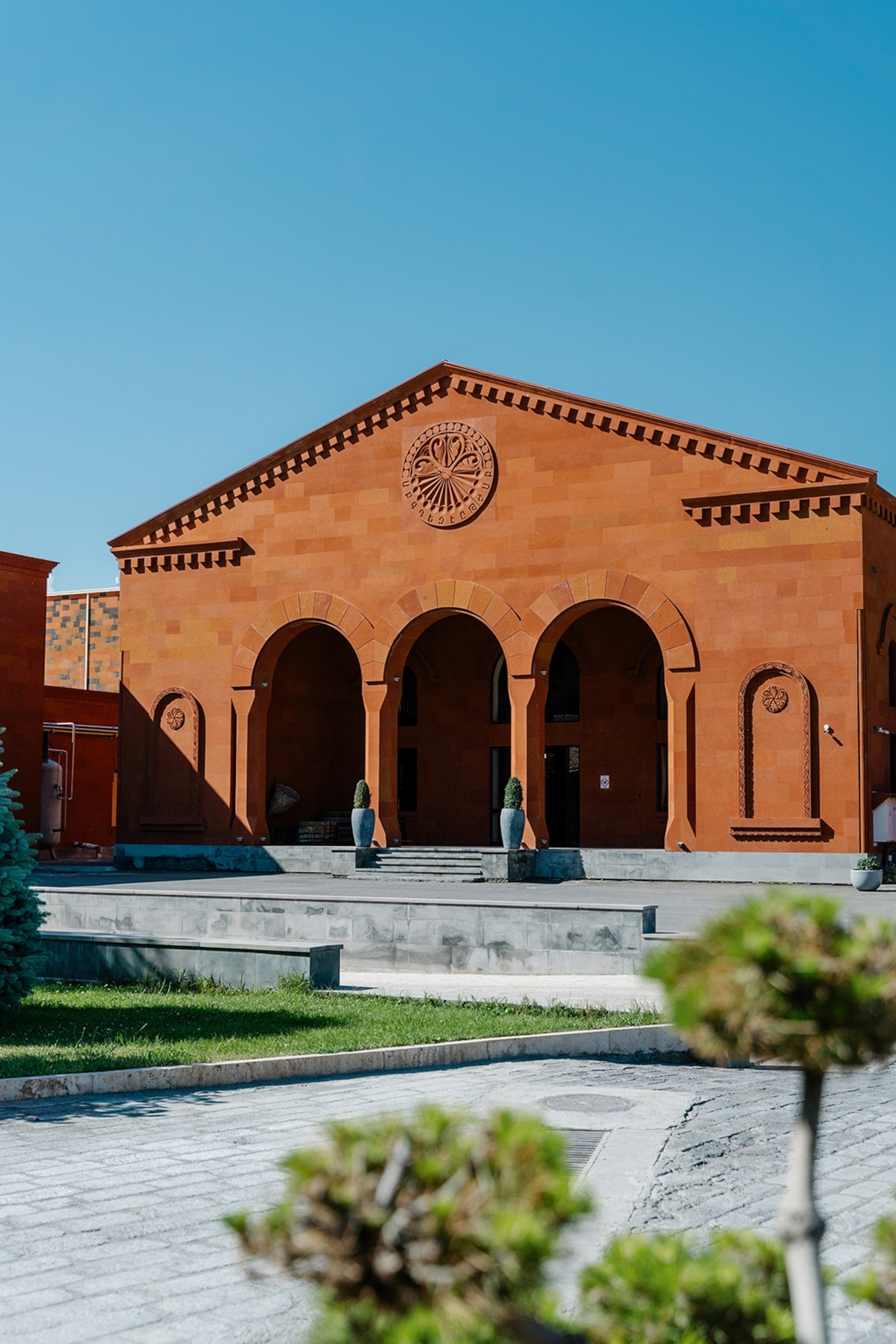A stone building with a flat facade and three arched entrances looking out on a plaza