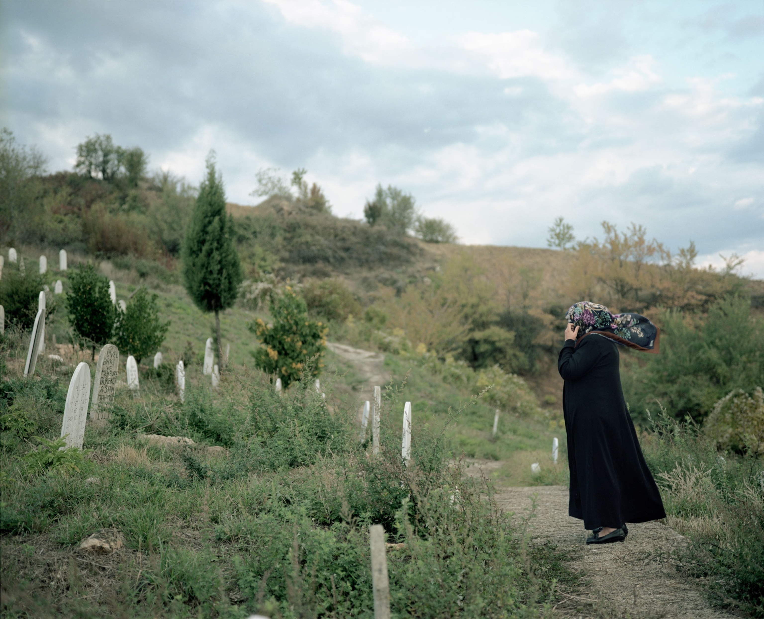 a Pomak woman praying in a cemetery in Greece