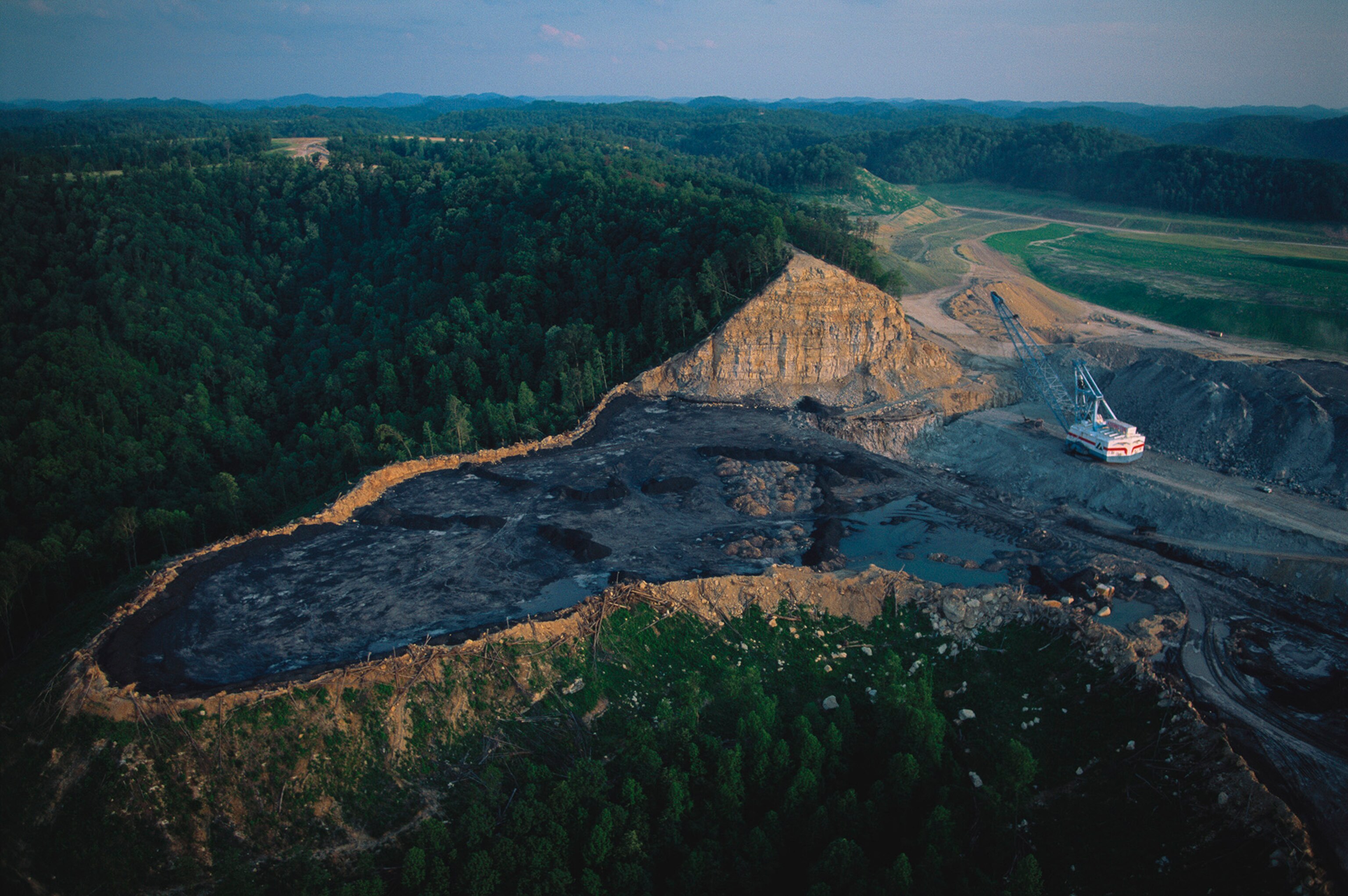 Leveling a mountain for coal in Appalachia. American mining companies get an exemption to national laws requiring them to return the land to its natural state after mining is finished. This is one of the poorest regions in the U.S., and mountain top mining is seen as a source of much-needed jobs. Here the mountain tops are blown off and dumped into river valleys to leave sprawling infertile mesas in what were once diverse temperate forests. Seven units of overburden are moved for every unit of coal extracted, which makes this marginally profitable economic activity have a huge environmental cost.