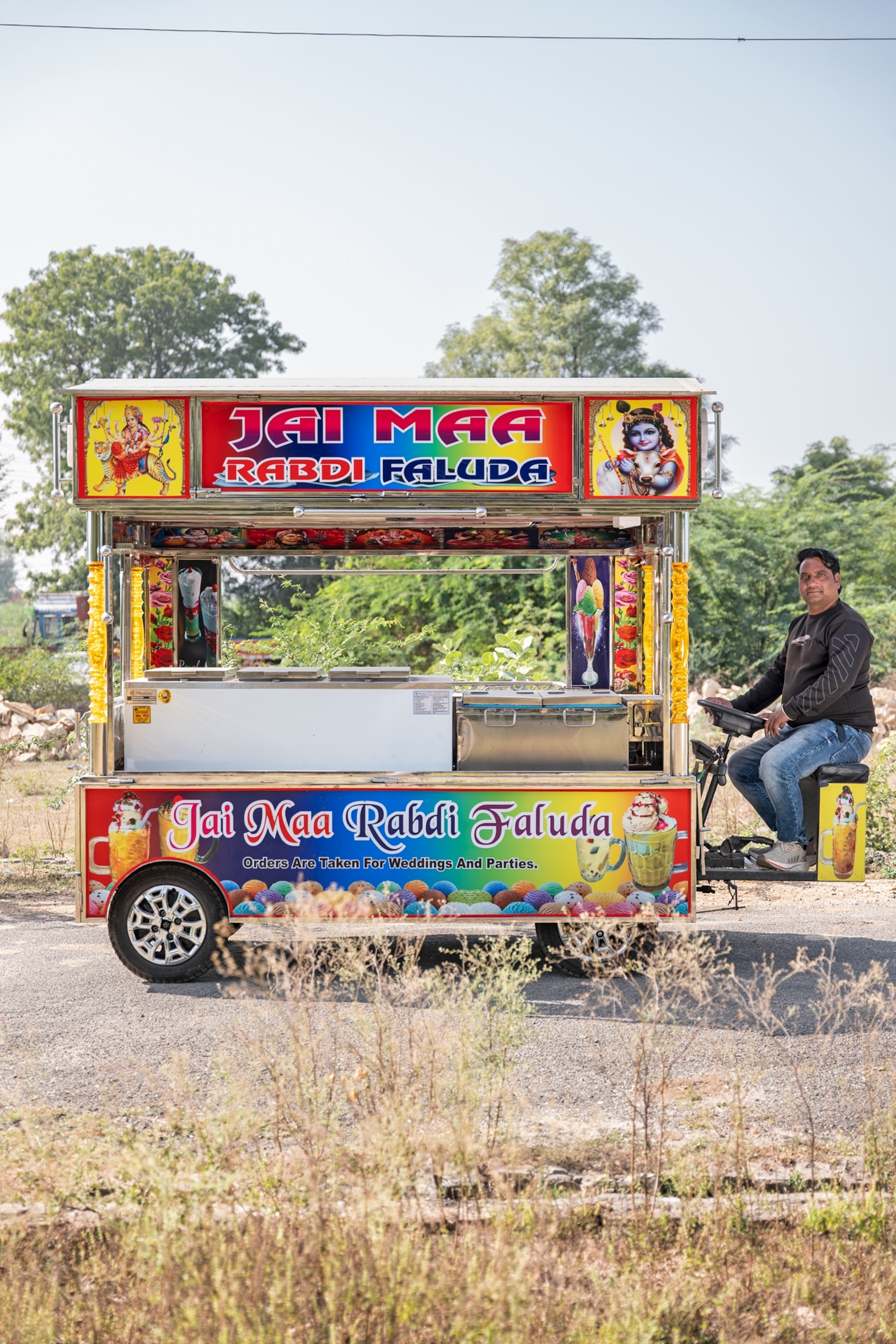 Man on the driver's seat of the colorful wagon looking into camera.