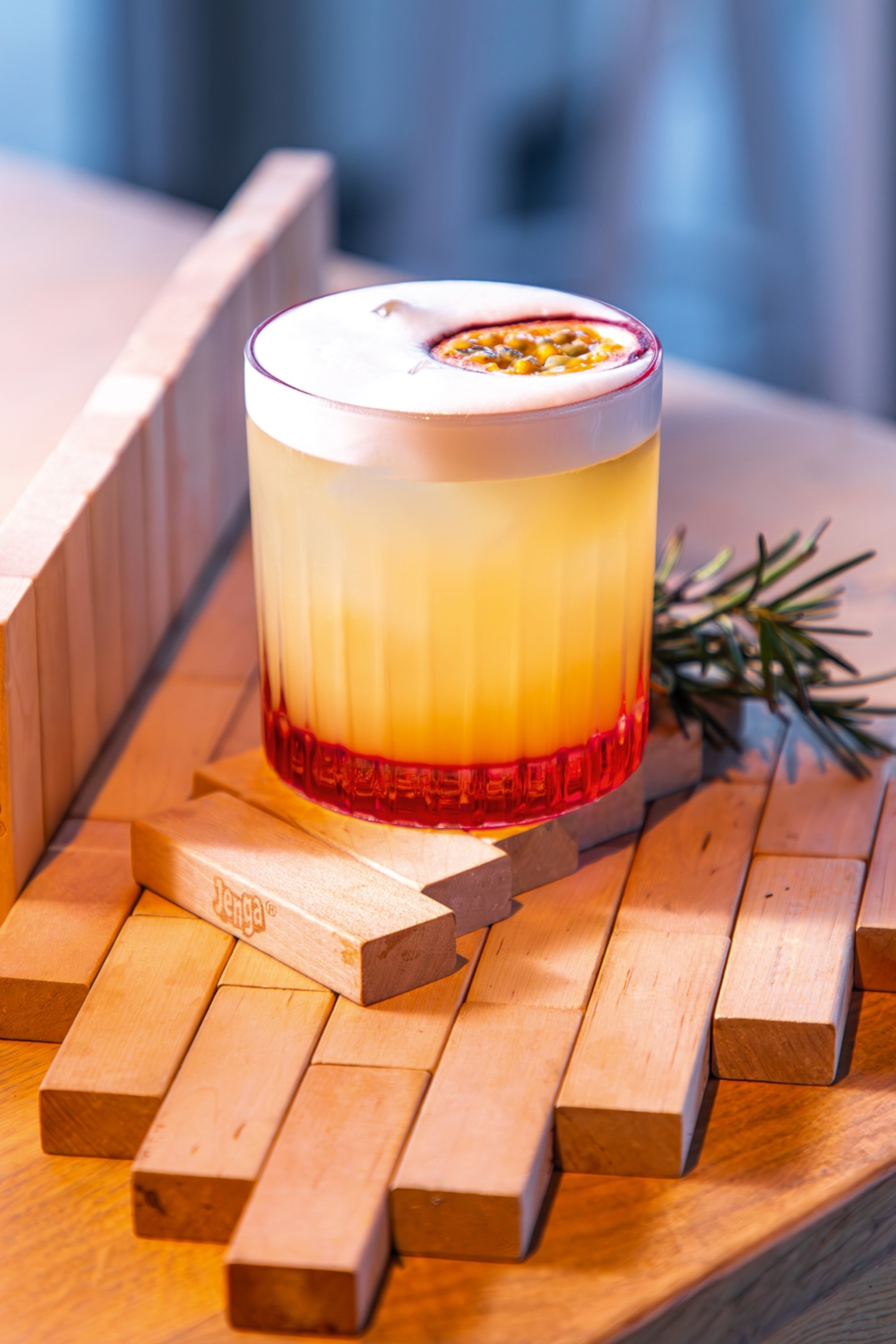 A close-up on a passionfruit-infused whiskey sour in a tumbler.