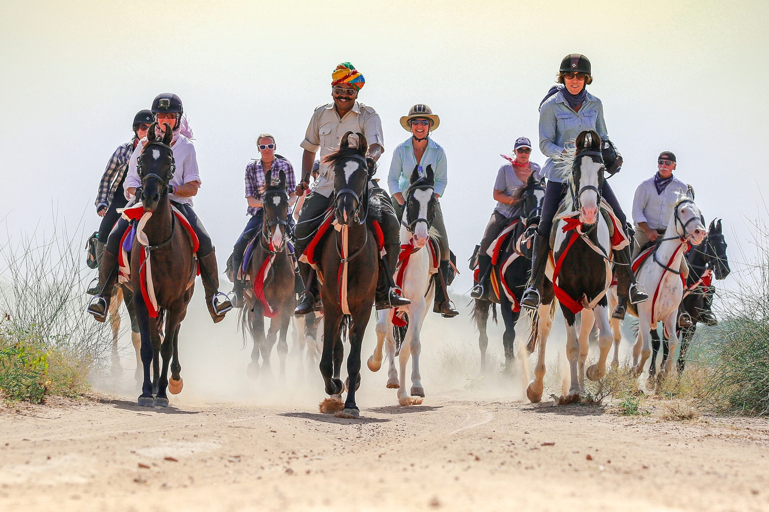 A group of riders on horses with a local guide from Rajasthan leading the group.
