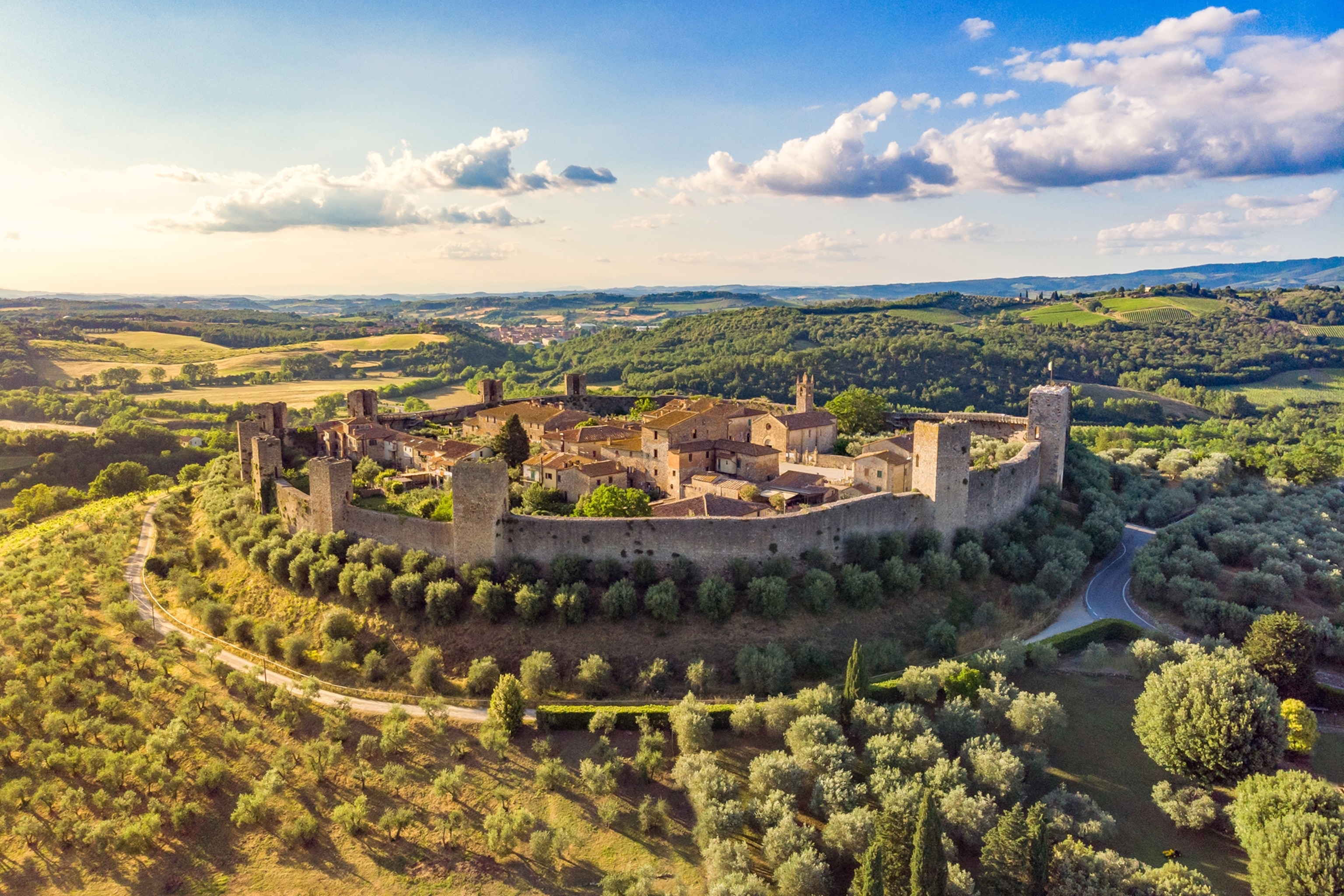 A walled medieval town in an Italian landscape with small hills.
