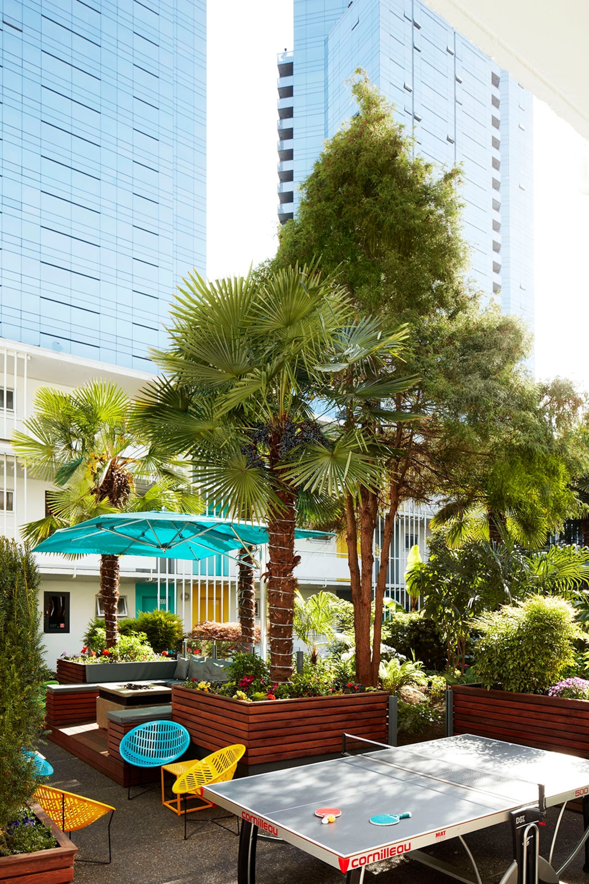 A ping pong table and chairs in a hotel's courtyard area with palm trees.