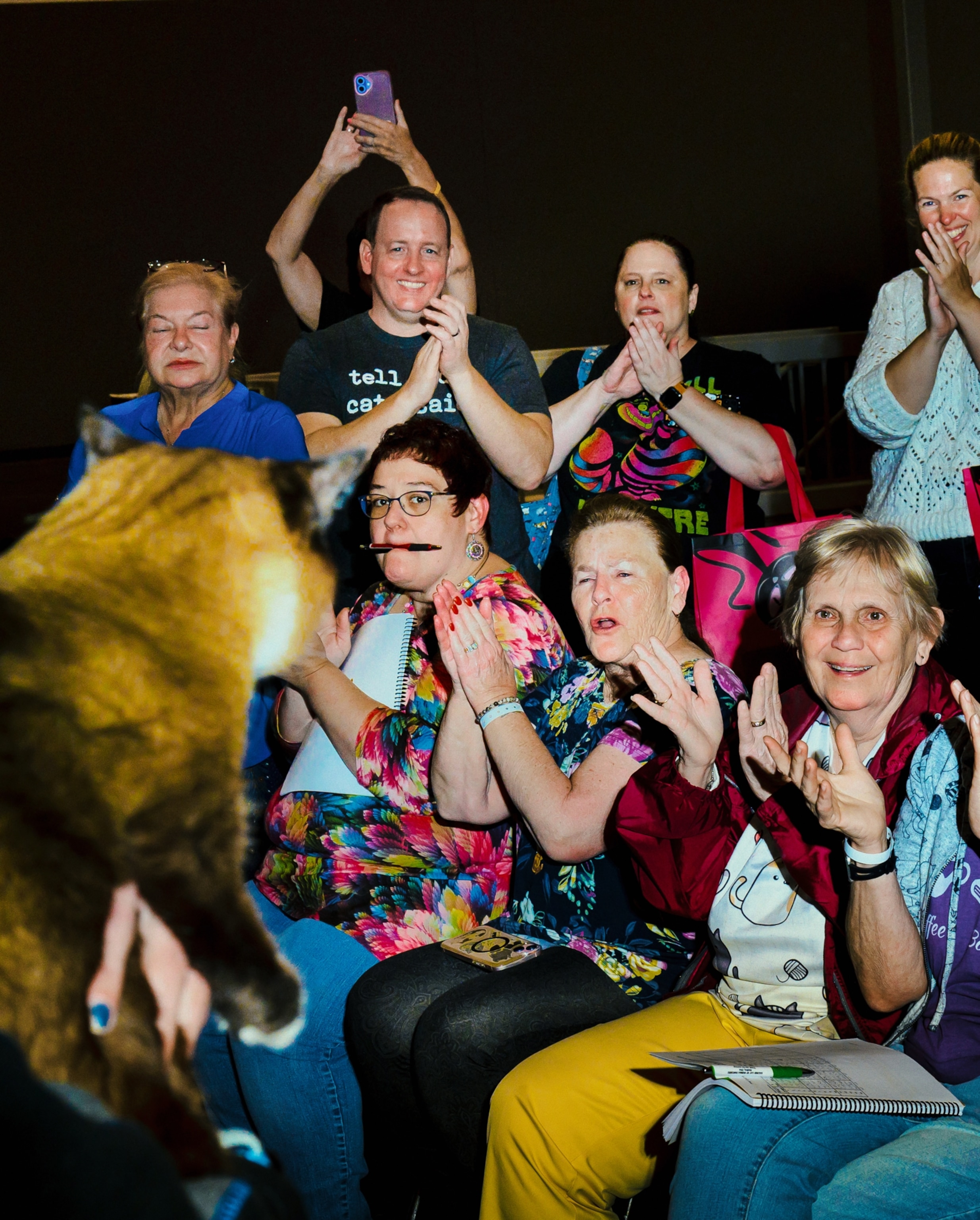 A crowd cheering for a cat, which is seen blurry in the foreground