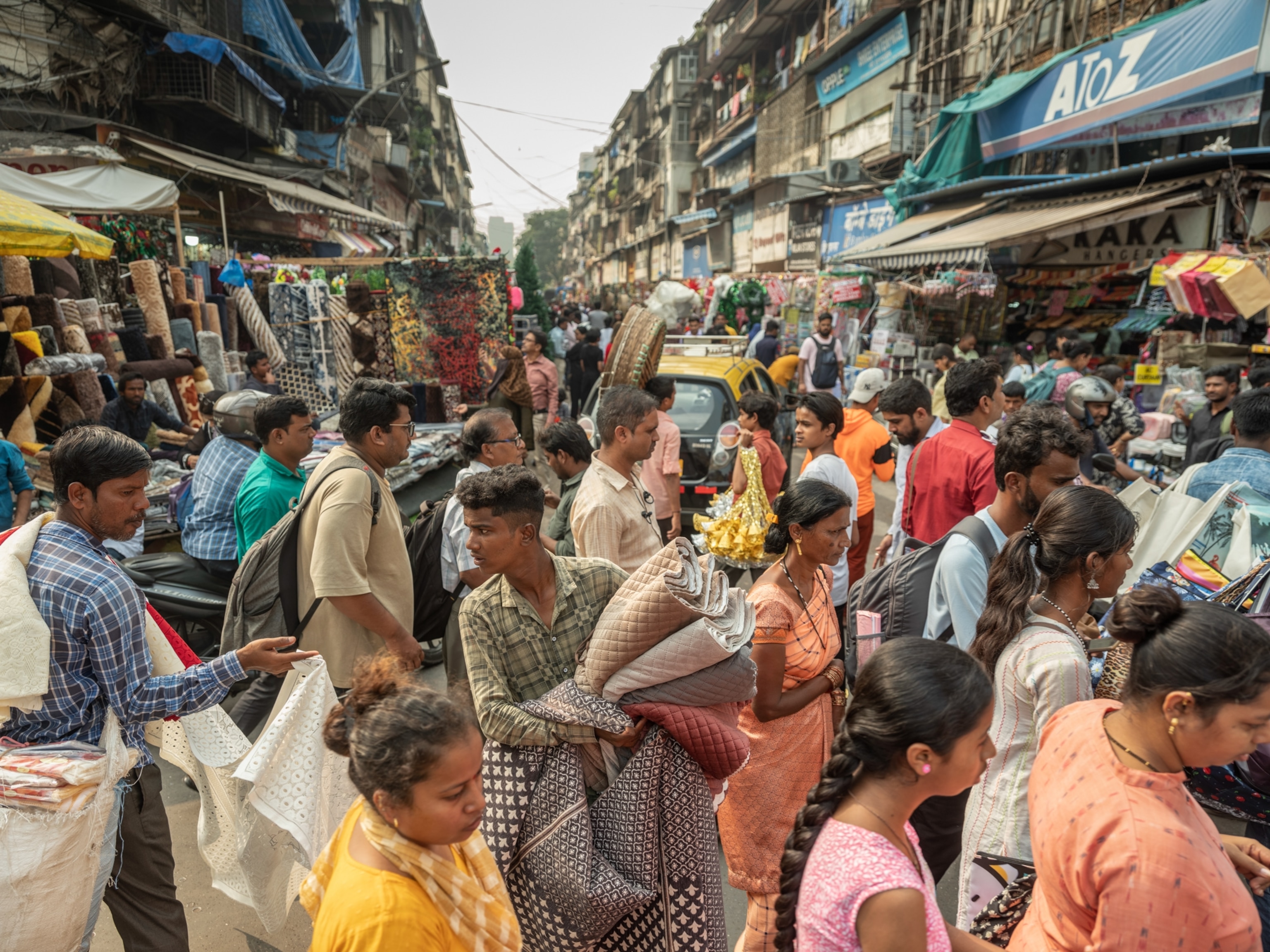 A crowd of people holding different textiles in a fabric market.