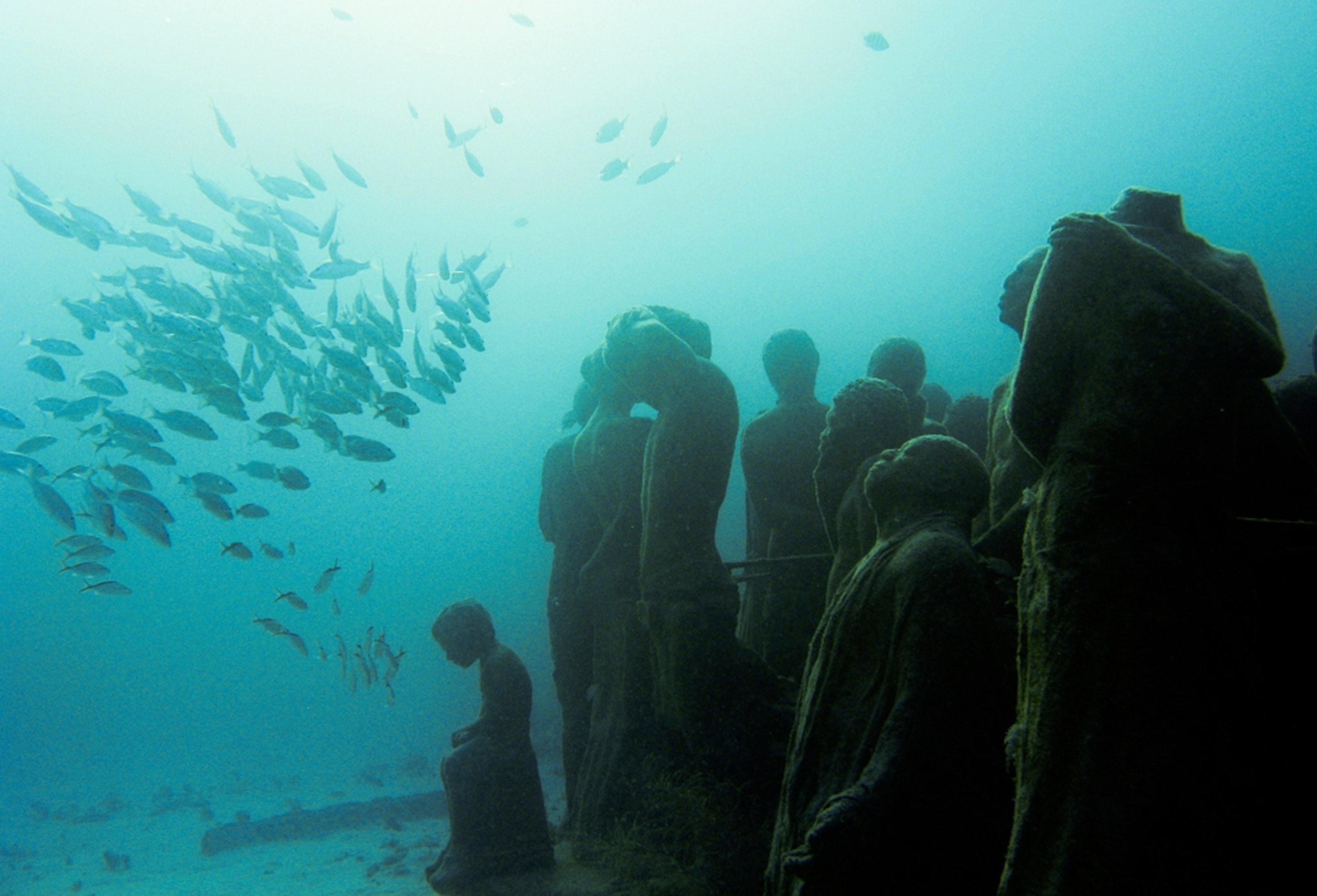 Fish swimming over sculptures -- picture from photo gallery on "The Silent Evolution" Caribbean underwater sculpture park off Cancun, Mexico