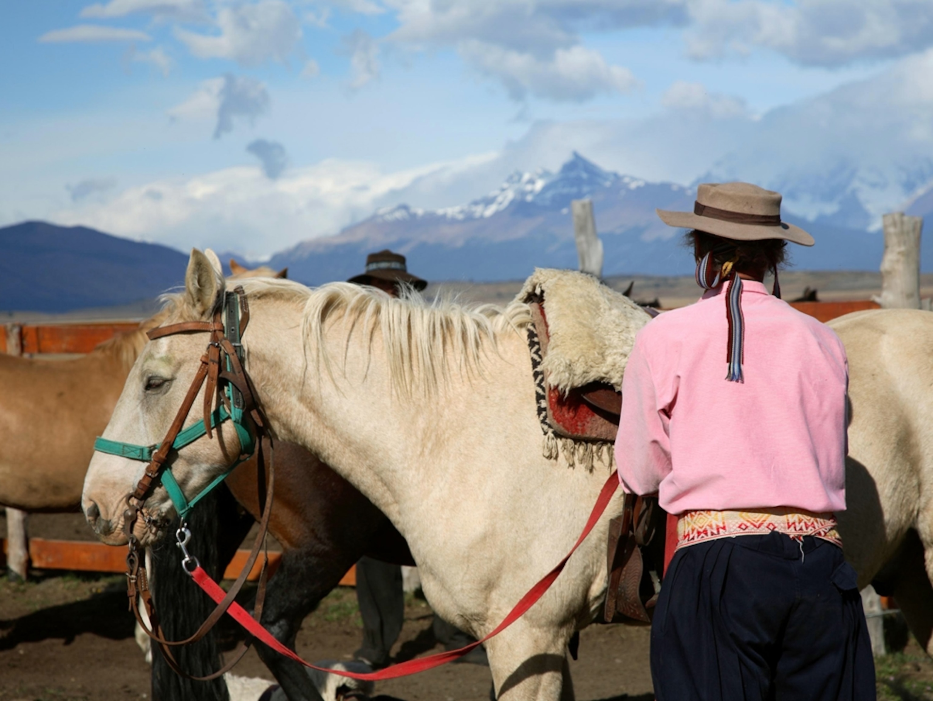 Men and horses pausing below mountains